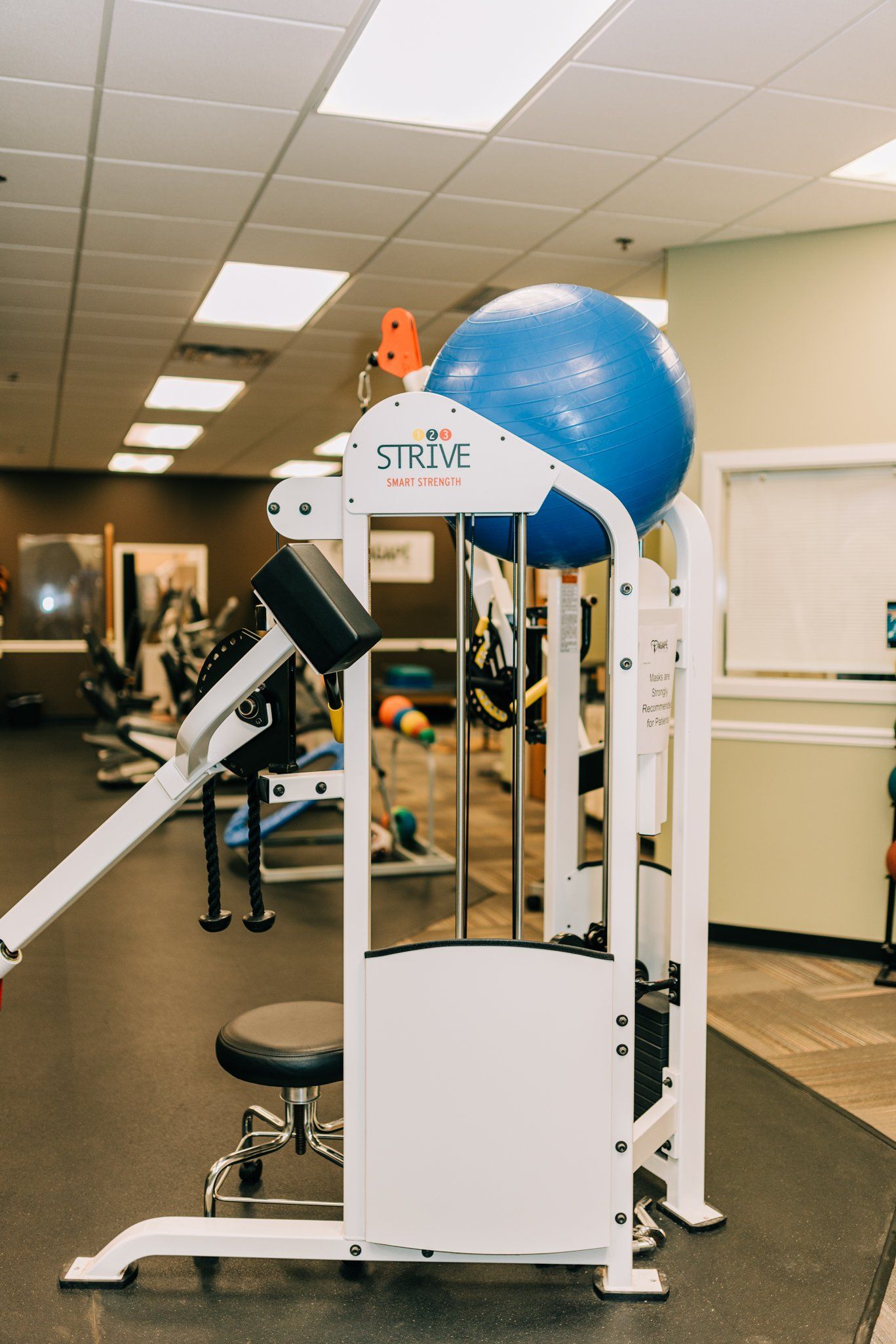 A blue exercise ball is sitting on top of a machine in a gym.