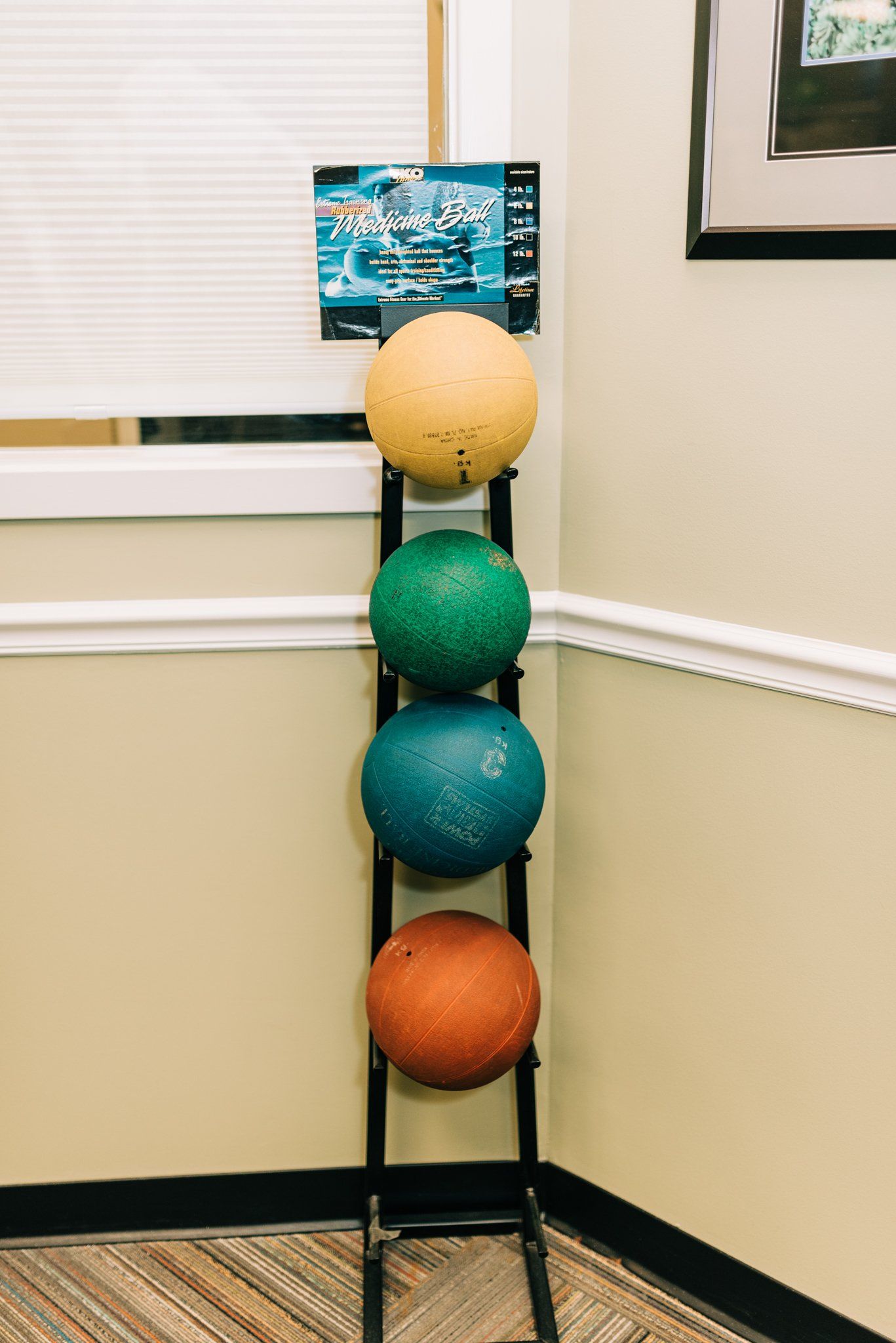 A row of exercise balls are stacked on top of each other on a rack.