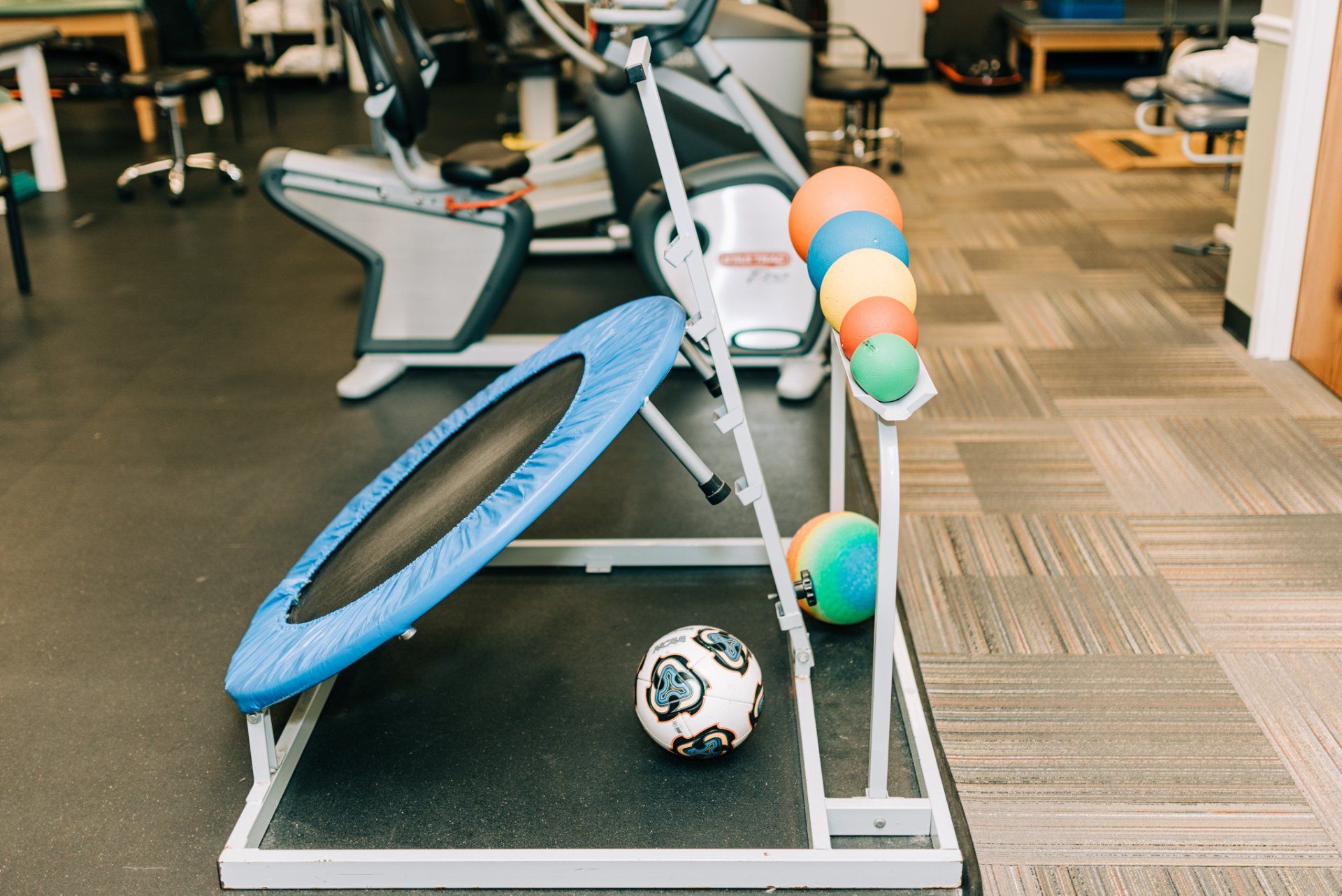A trampoline and a soccer ball are on display in a gym.