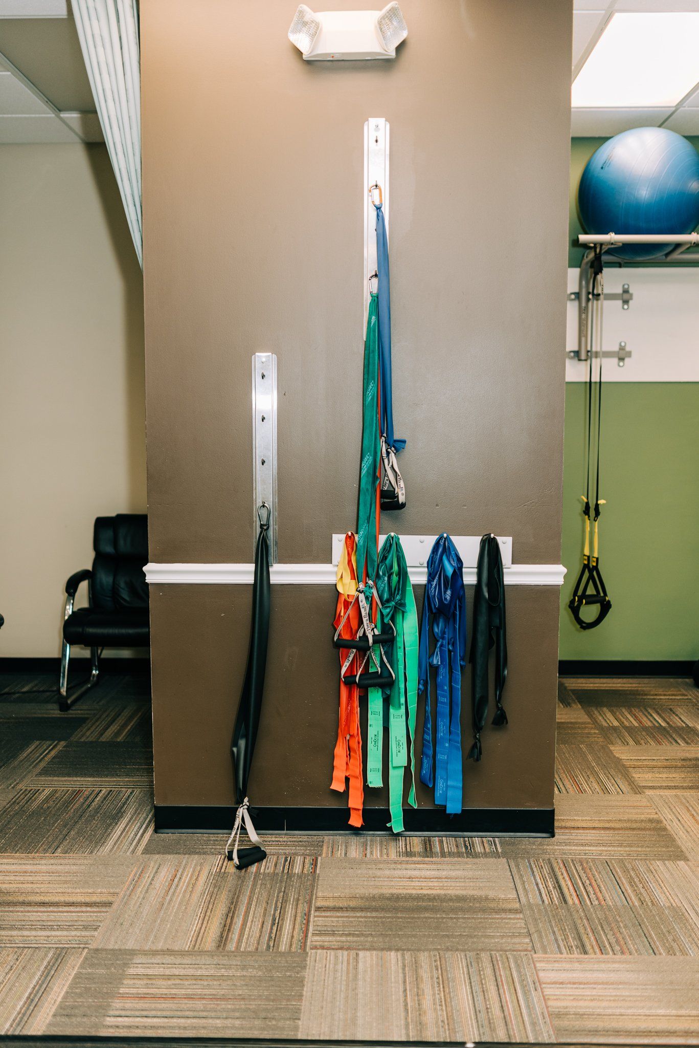 A bunch of exercise bands are hanging on a wall in a gym.