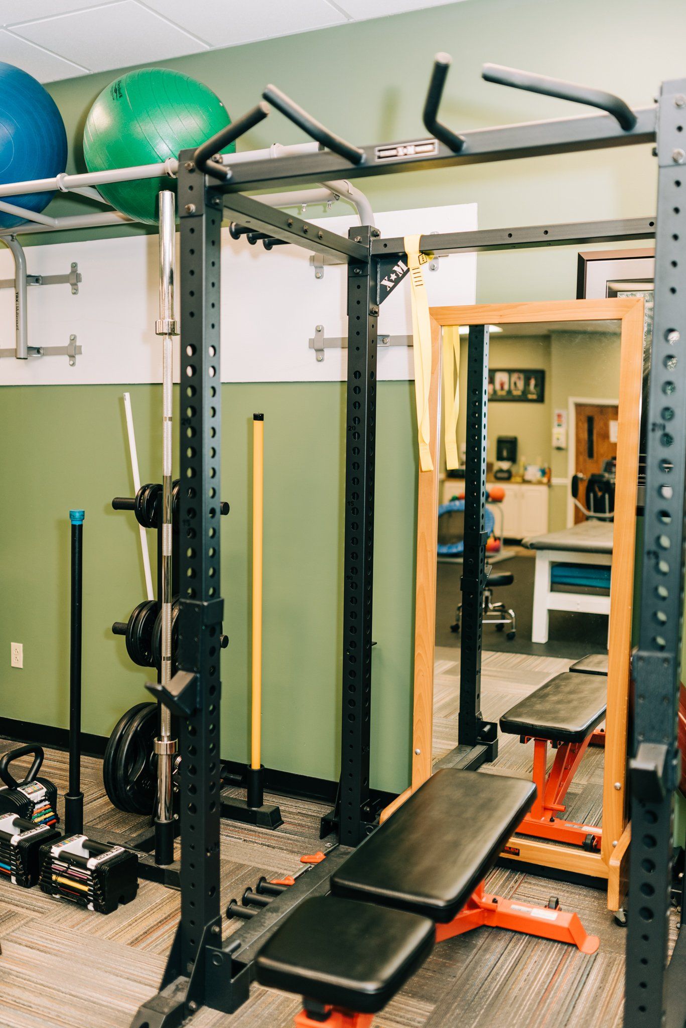 A gym with a bench , barbells , and a mirror.