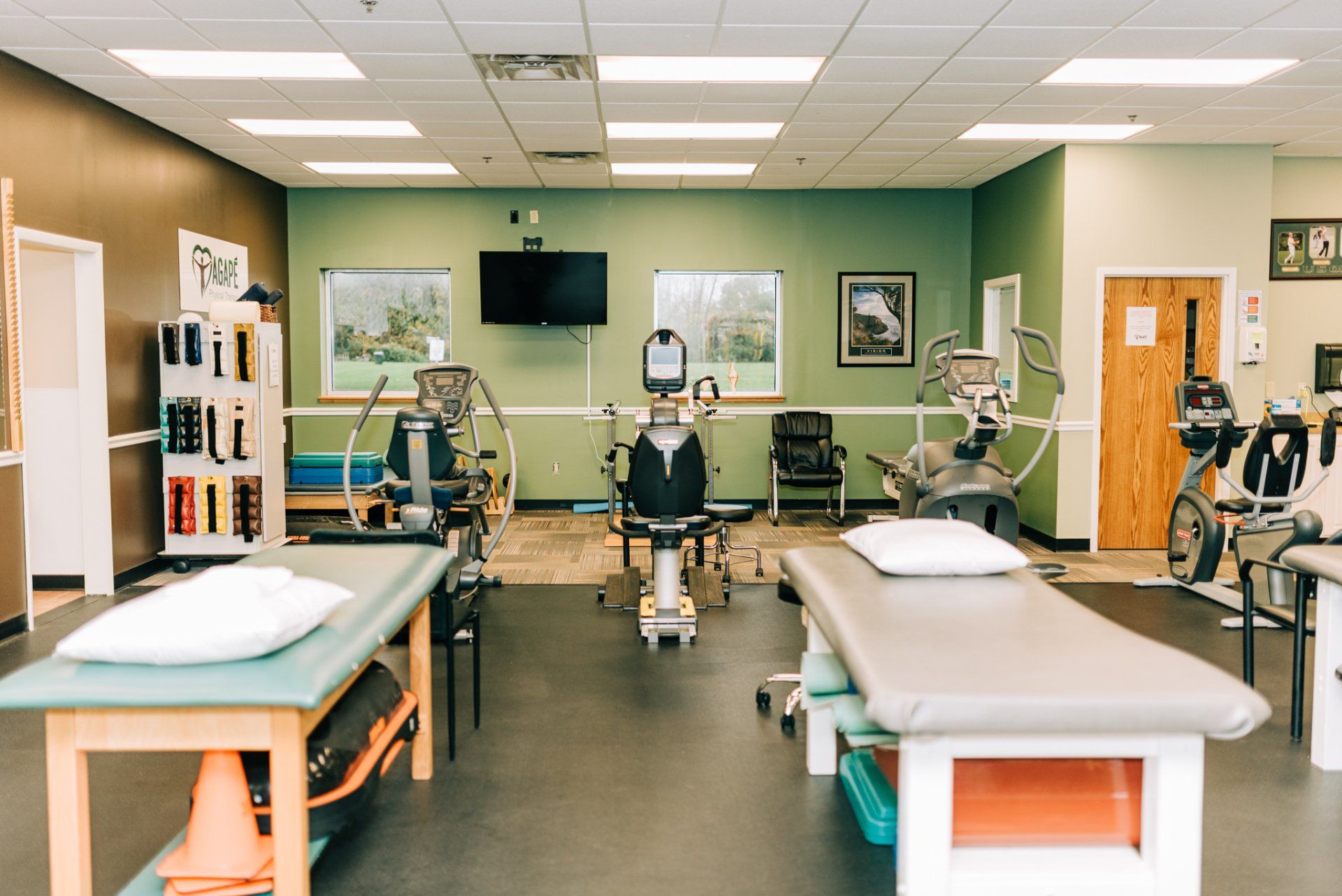 A physical therapy room with a lot of tables and exercise equipment.
