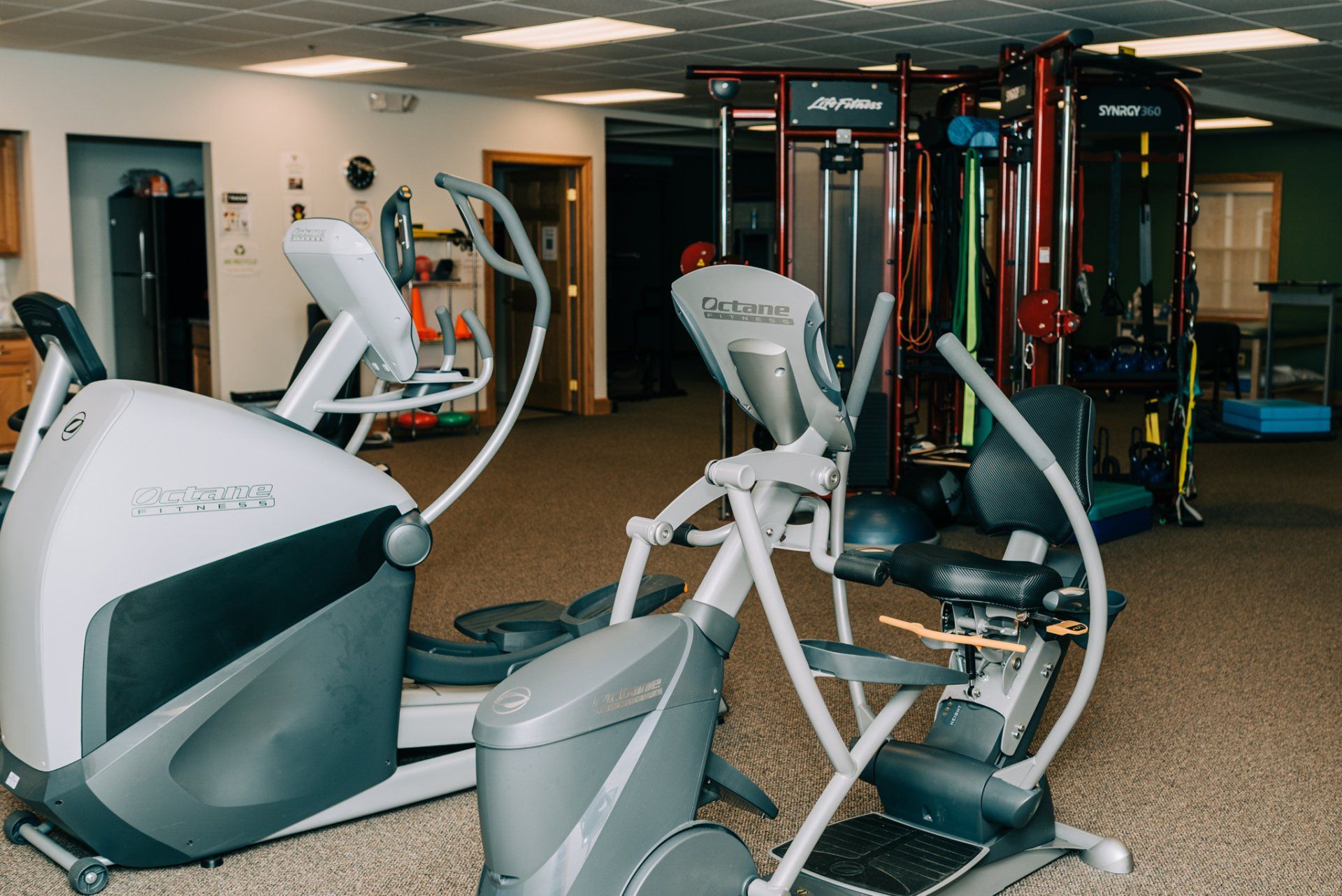 Two ellipticals are sitting next to each other in a gym.
