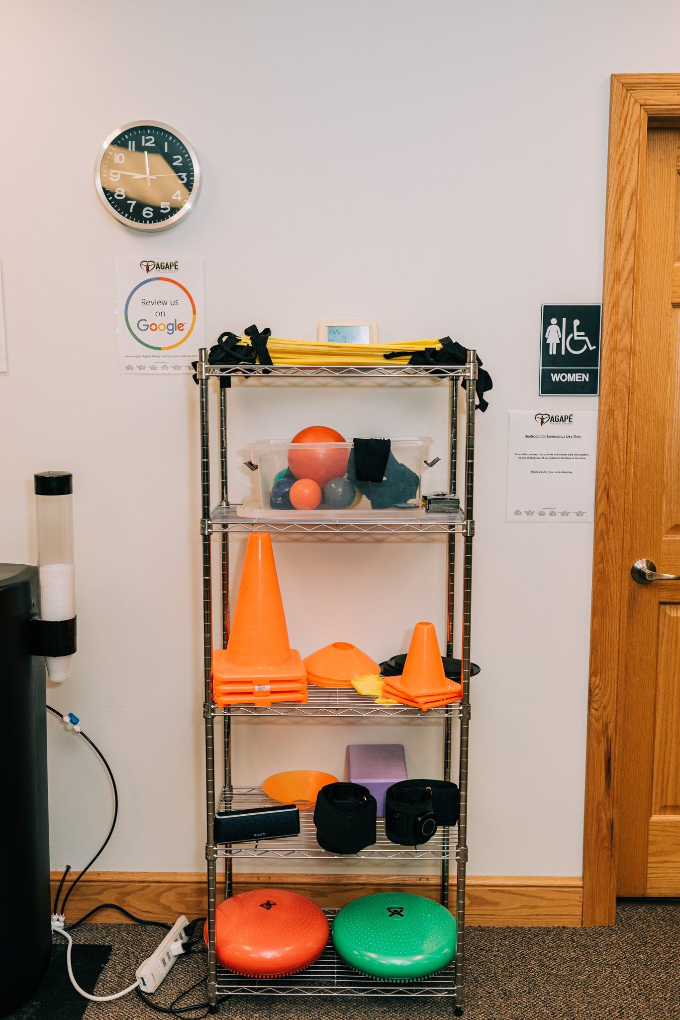 A shelf filled with exercise equipment and a clock on the wall.