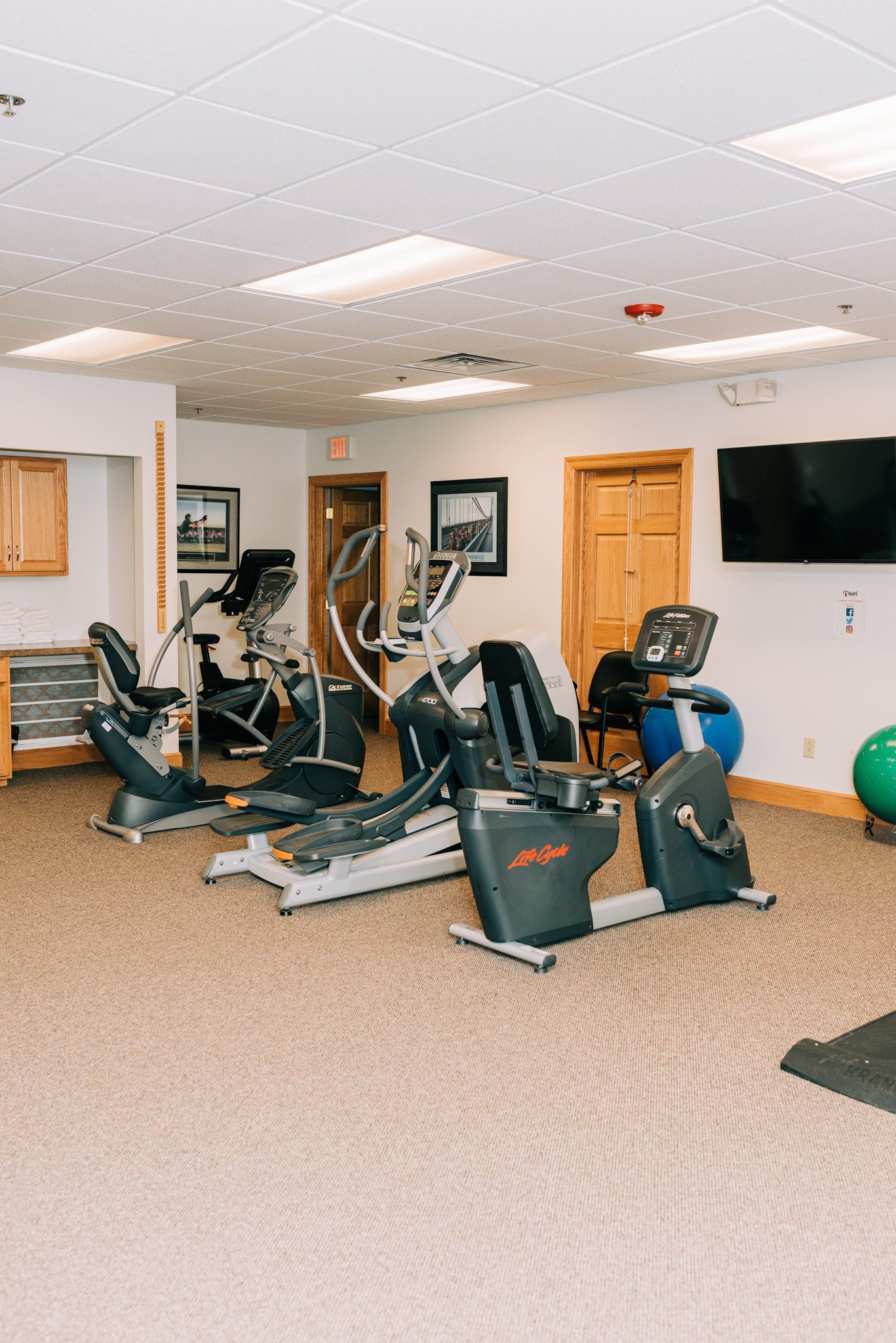 A gym with a lot of exercise equipment and a flat screen tv.