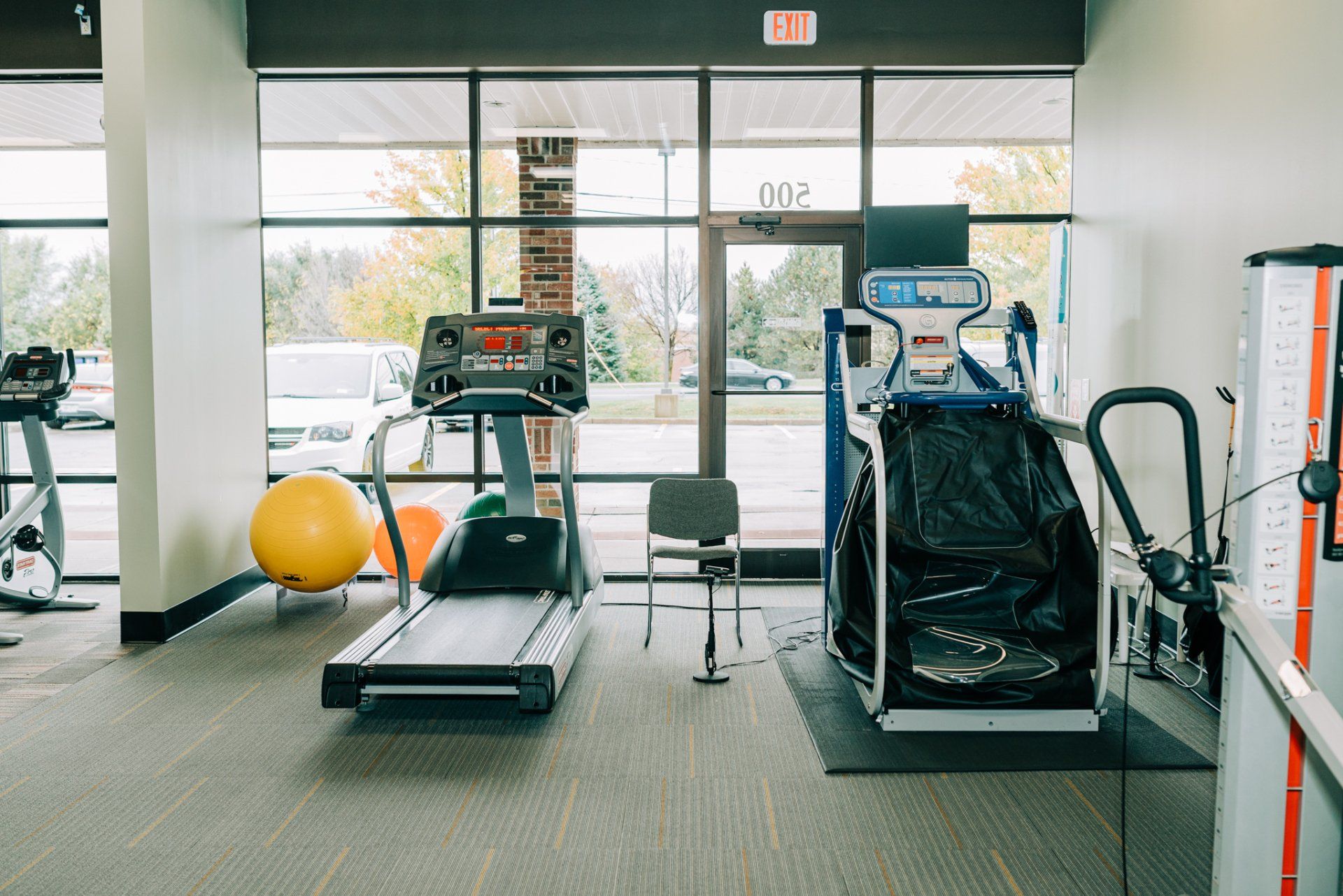 A gym with treadmills , exercise balls , and a chair.