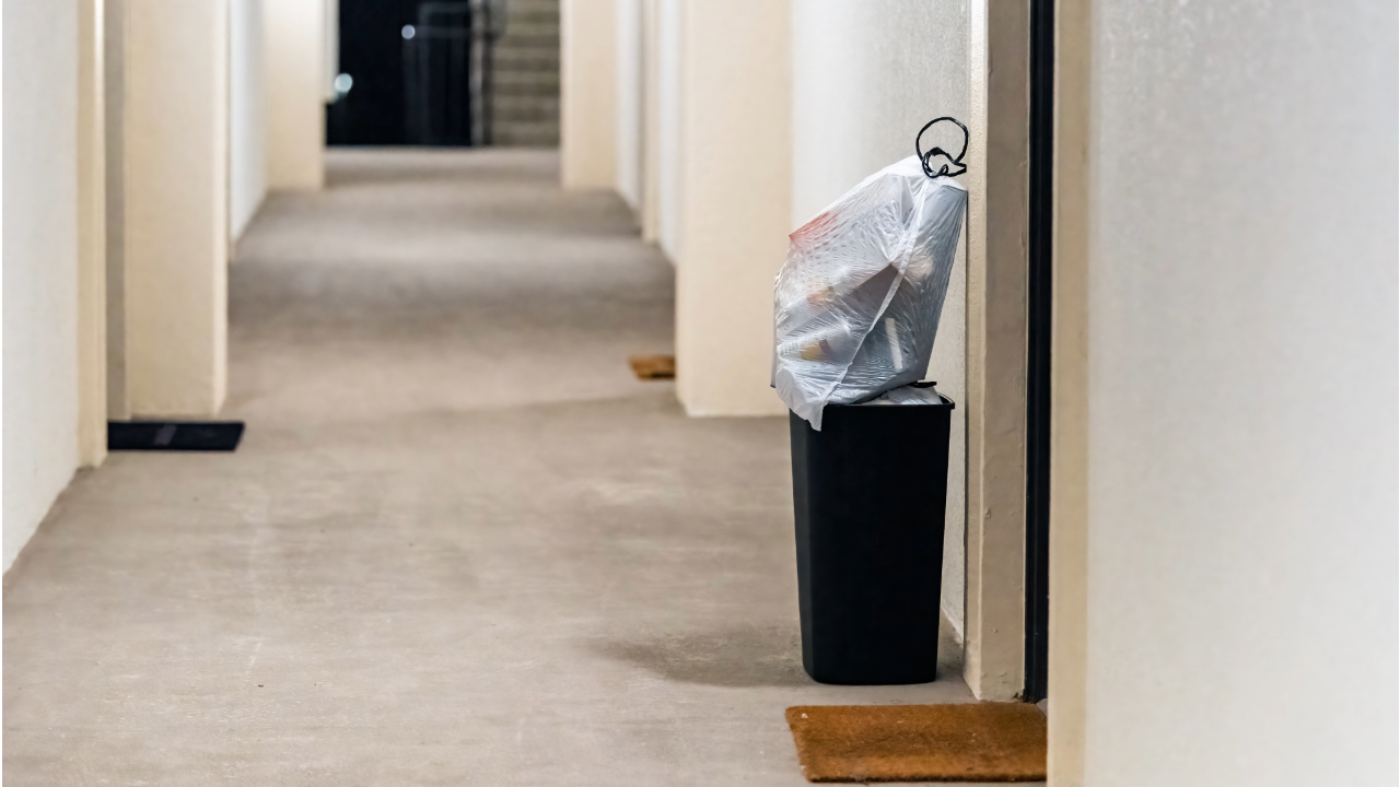 A trash can is sitting in a hallway next to a door.