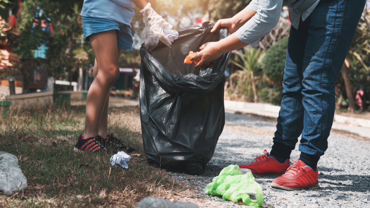 A man and a woman are picking up trash in a park.