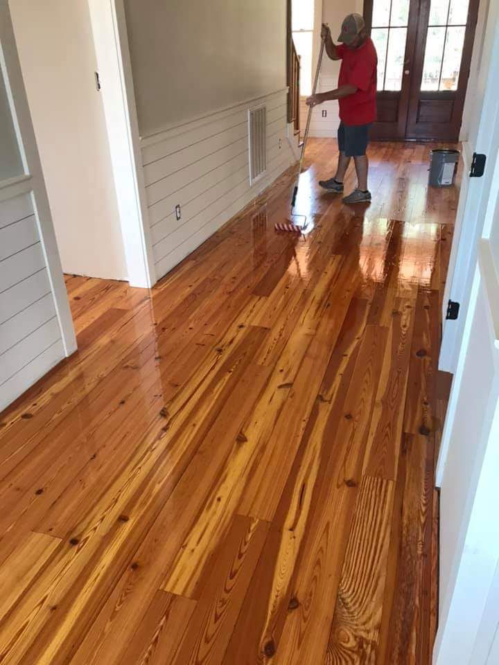 A man is cleaning a wooden floor with a mop.