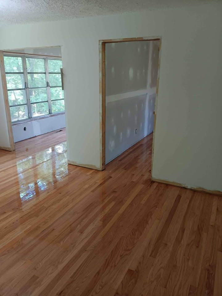 An empty room with hardwood floors and white walls.