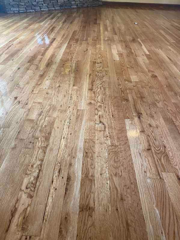 A man is installing a wooden floor with a hammer.