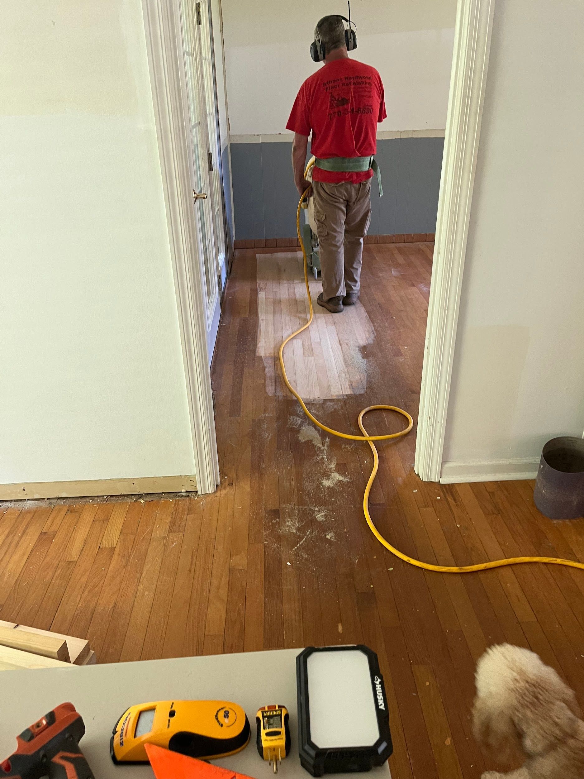 A man is standing in a hallway next to a dog.