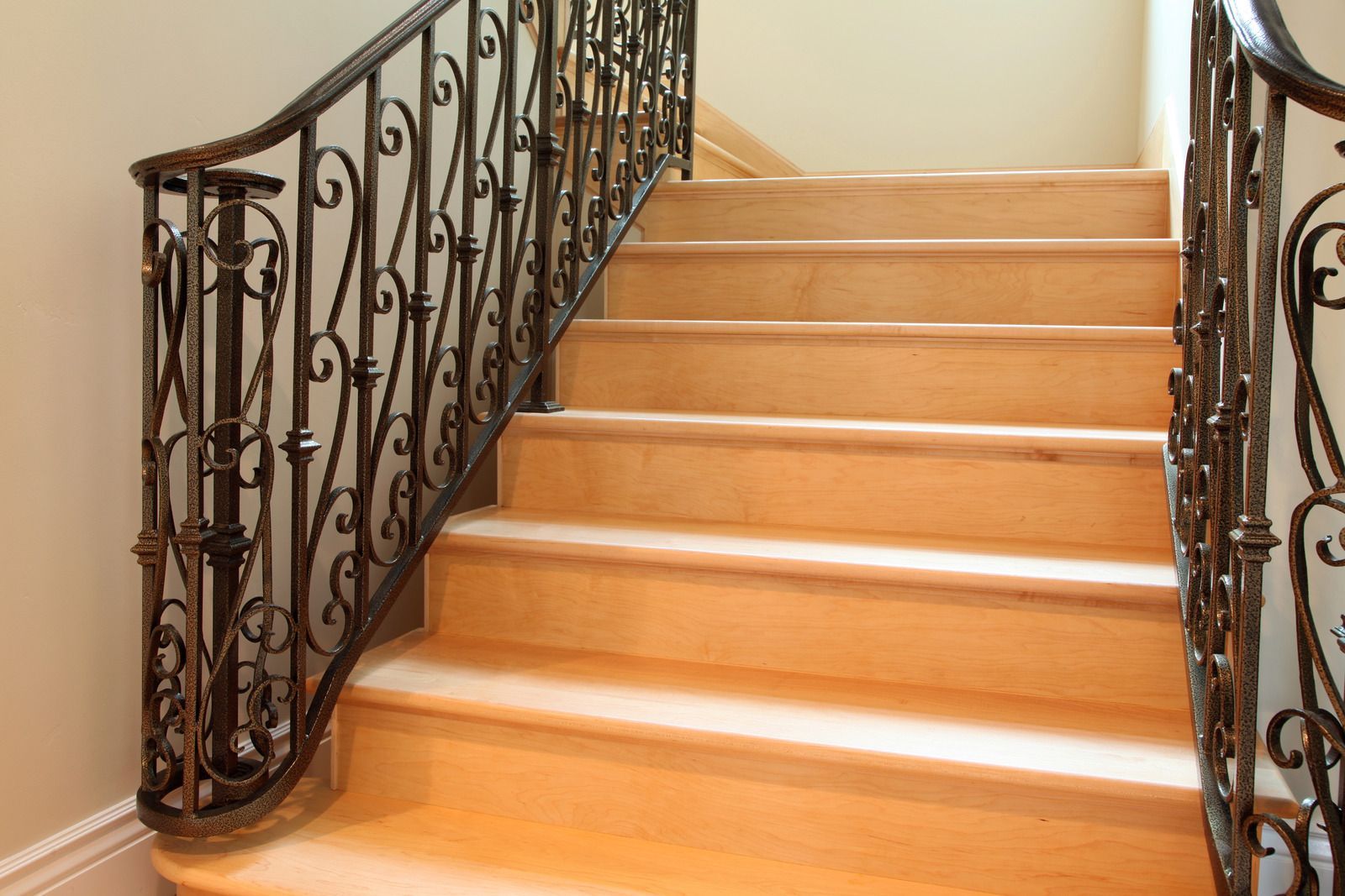 A set of wooden stairs with a wrought iron railing