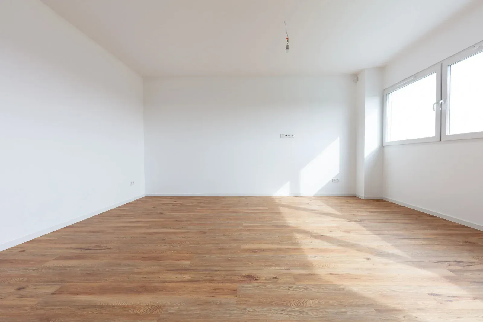 An empty room with hardwood floors and white walls.
