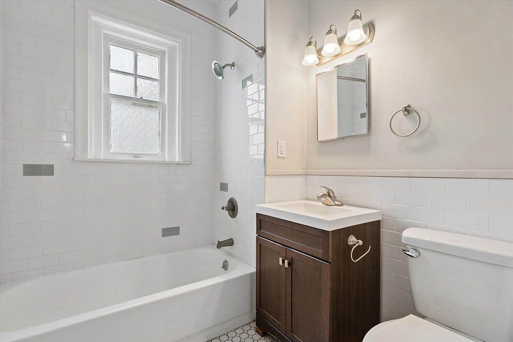 A bathroom with a sink , toilet , tub and mirror.