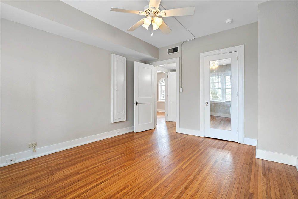 An empty room with hardwood floors and a ceiling fan.