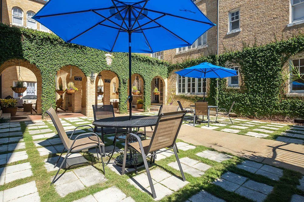 A patio with a table and chairs under blue umbrellas.