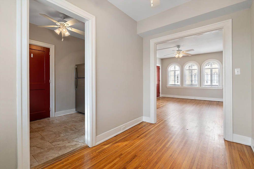 A hallway in a house with hardwood floors and a ceiling fan.