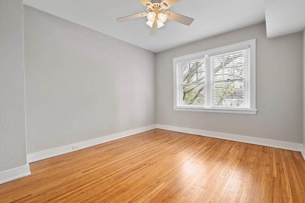 An empty room with hardwood floors and a ceiling fan.