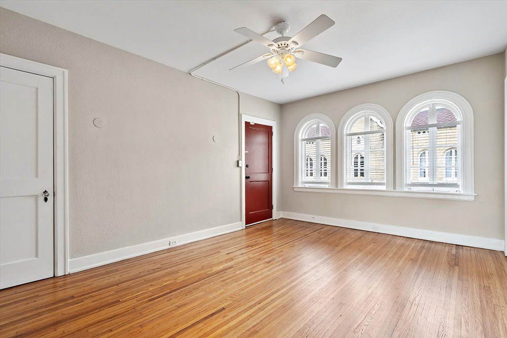 An empty living room with hardwood floors and a ceiling fan.
