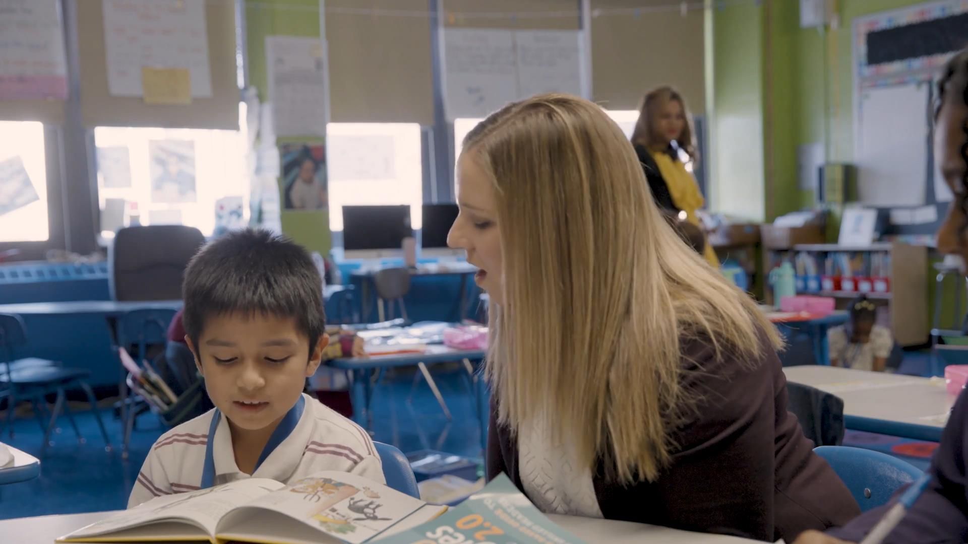 Dr. Macie Kerbs is reading a book to a young boy in a classroom implementing Texas Literacy Strategies by Jennifer Serravallo