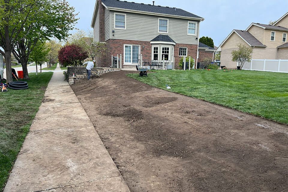 Finished grading and yard leveling creating a smooth, properly sloped surface to improve drainage around a residential home