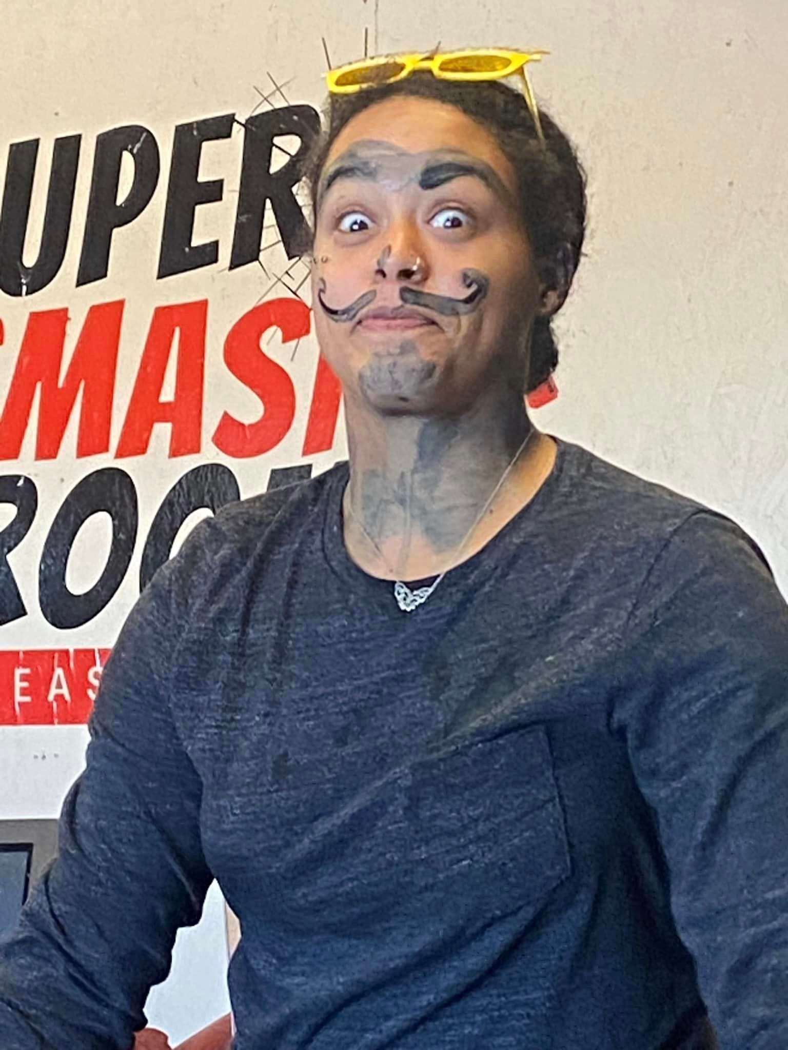 A man with a fake mustache and sunglasses on his head.