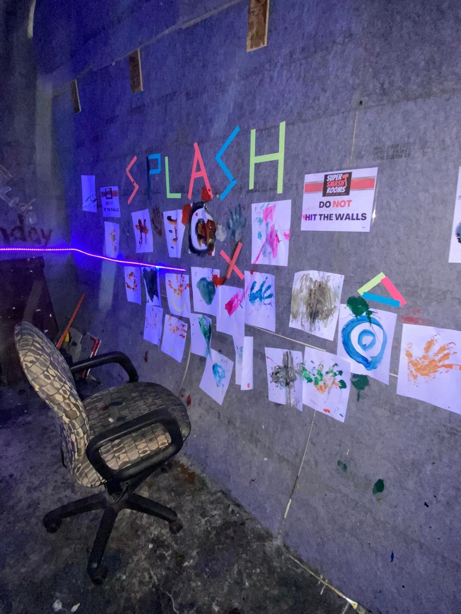 A chair is sitting in front of a wall with drawings on it.