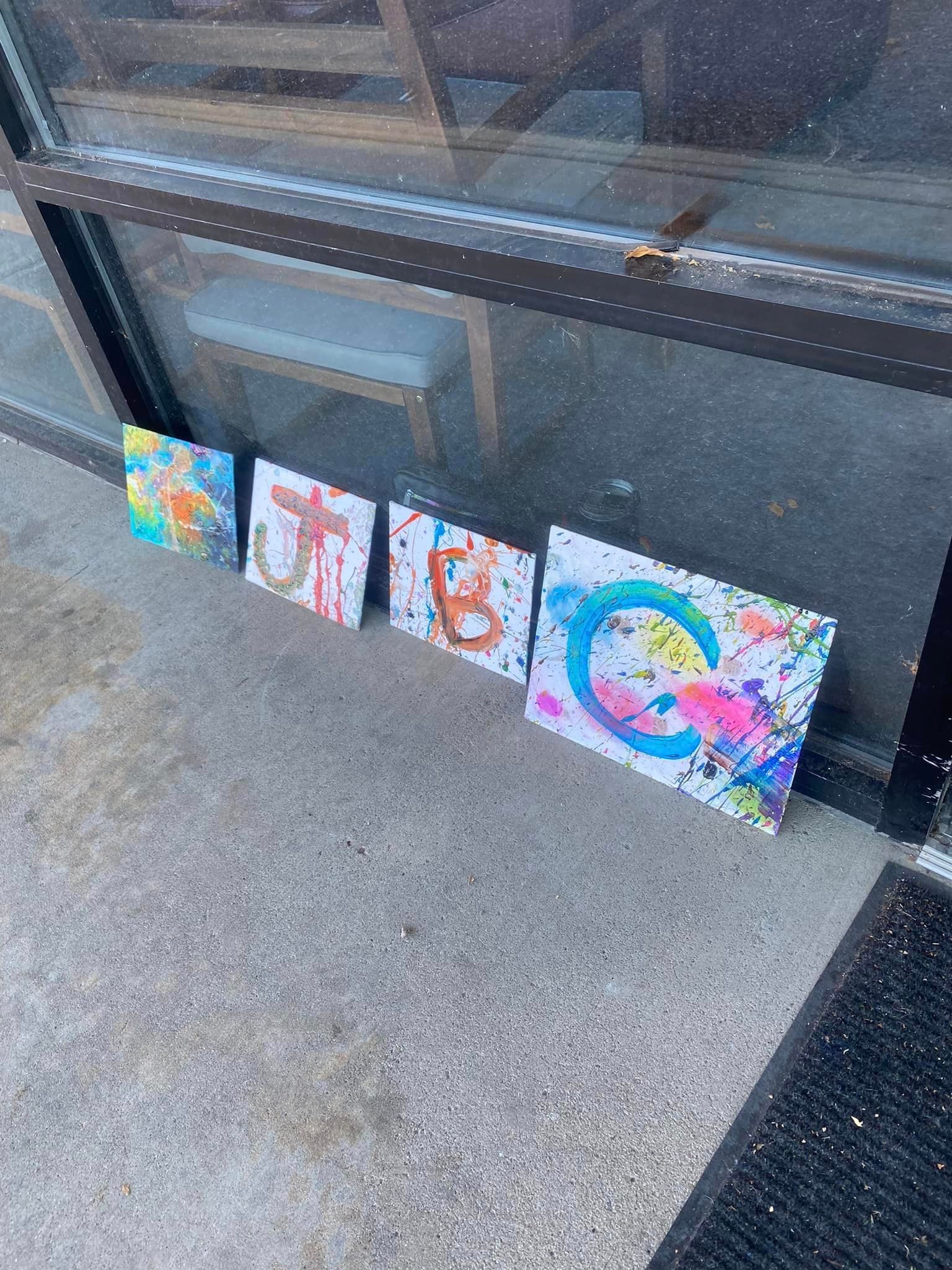 A bunch of paintings are sitting on the ground in front of a window.