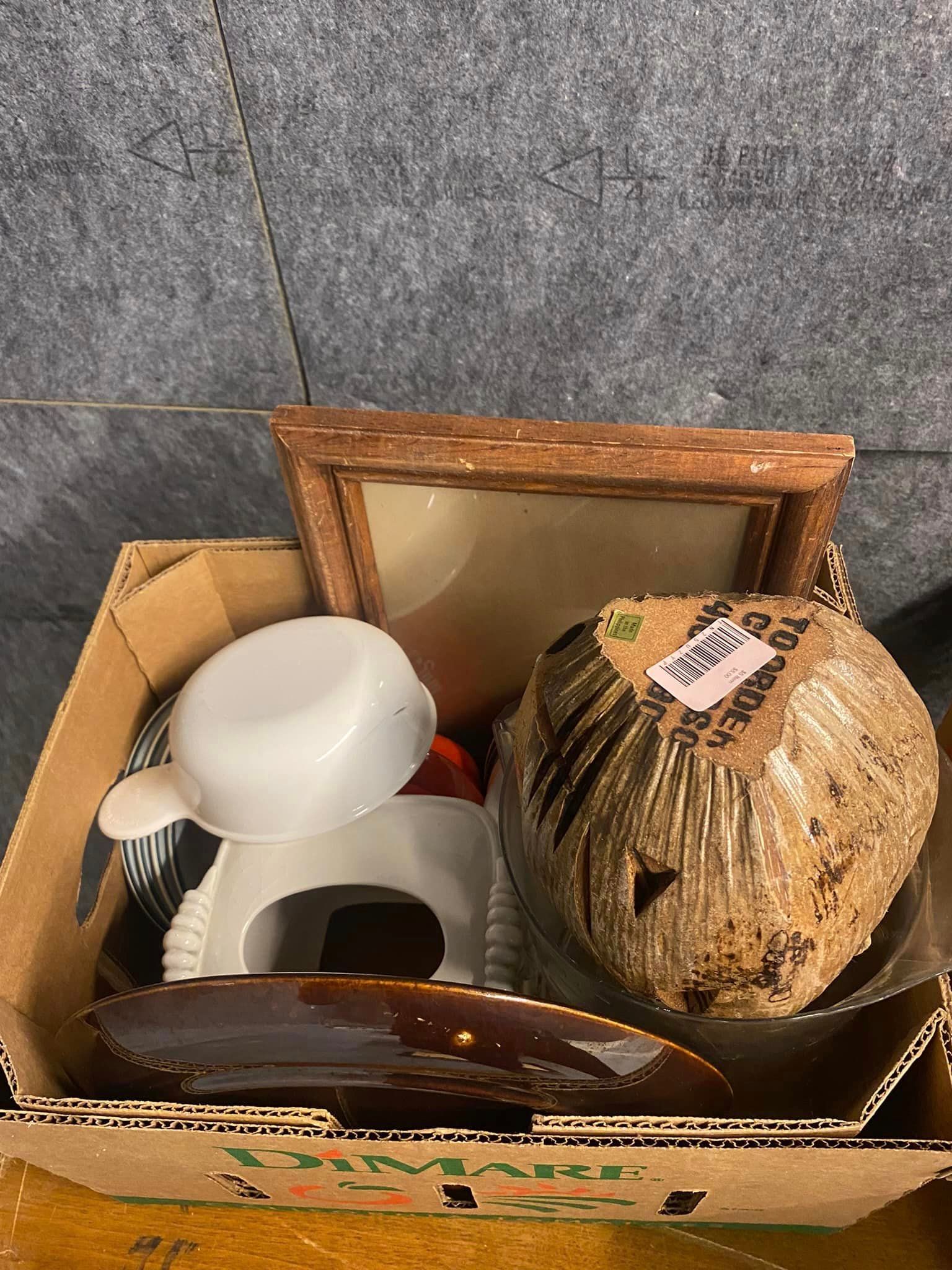 A cardboard box filled with a variety of items , including a picture frame.