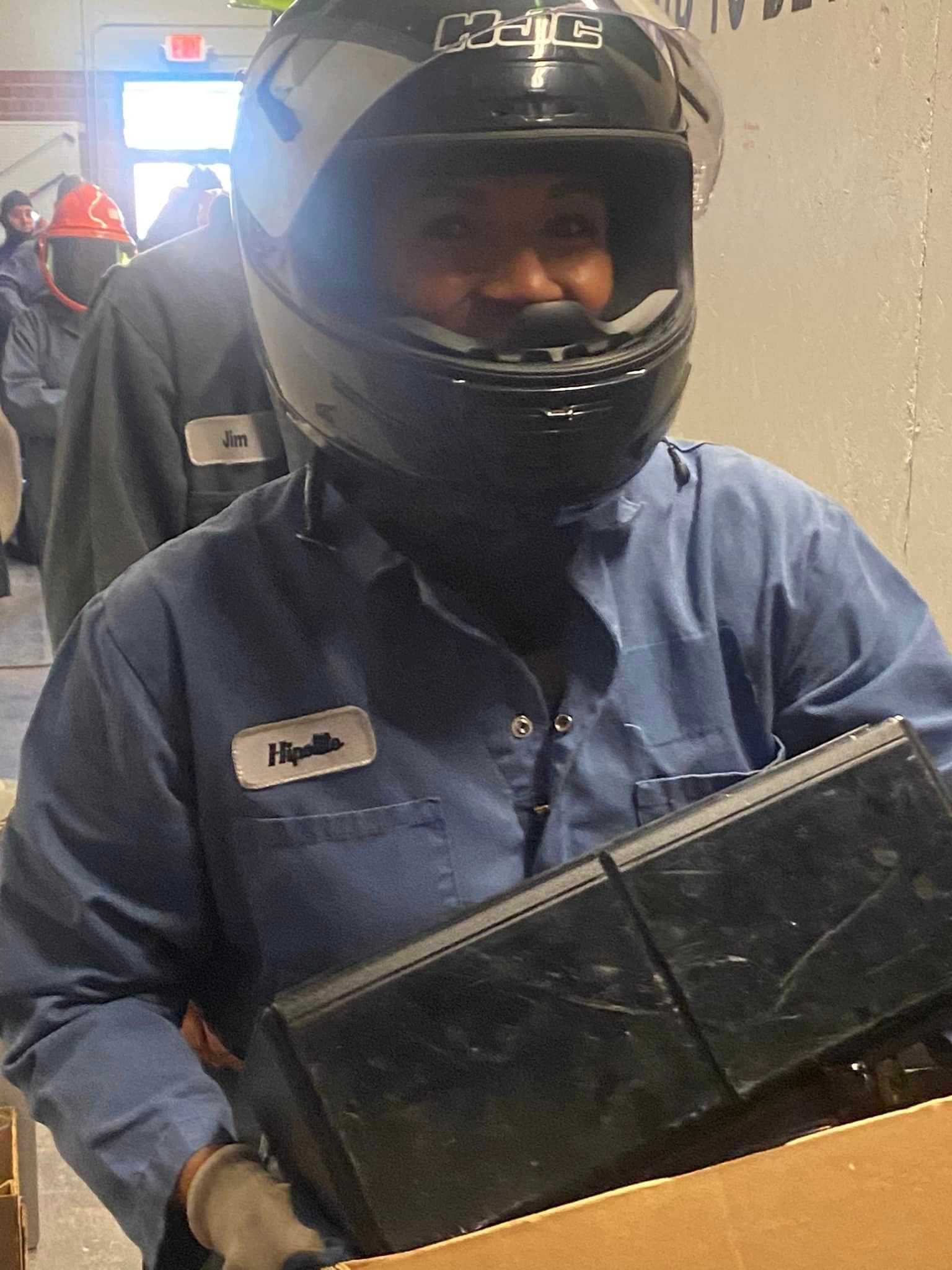 A man wearing a helmet is holding a box