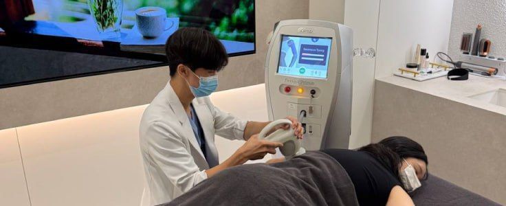A modern, elegant office waiting area with a curved beige sofa, matching armchairs, white marble floors, and art on walls.