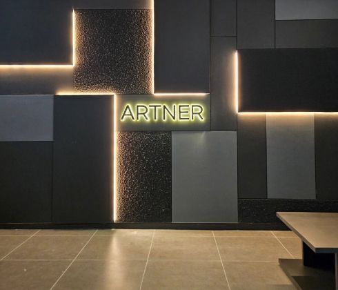 Modern lobby featuring white marble floors, a curved beige sofa, armchairs, a reception desk, and a burgundy accent wall.