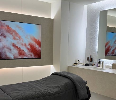 A corridor with deep red arched walls and ceiling, featuring white tiled floors and white doorways in the background.
