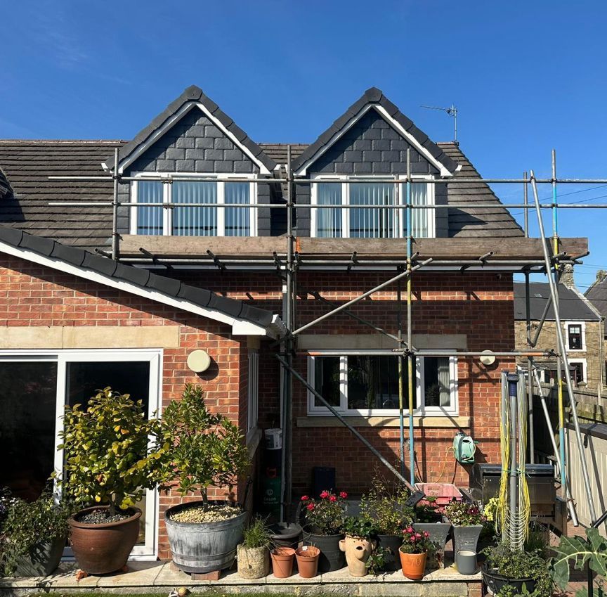 Front view of a house with scaffold erected in preparation for a roof repair.