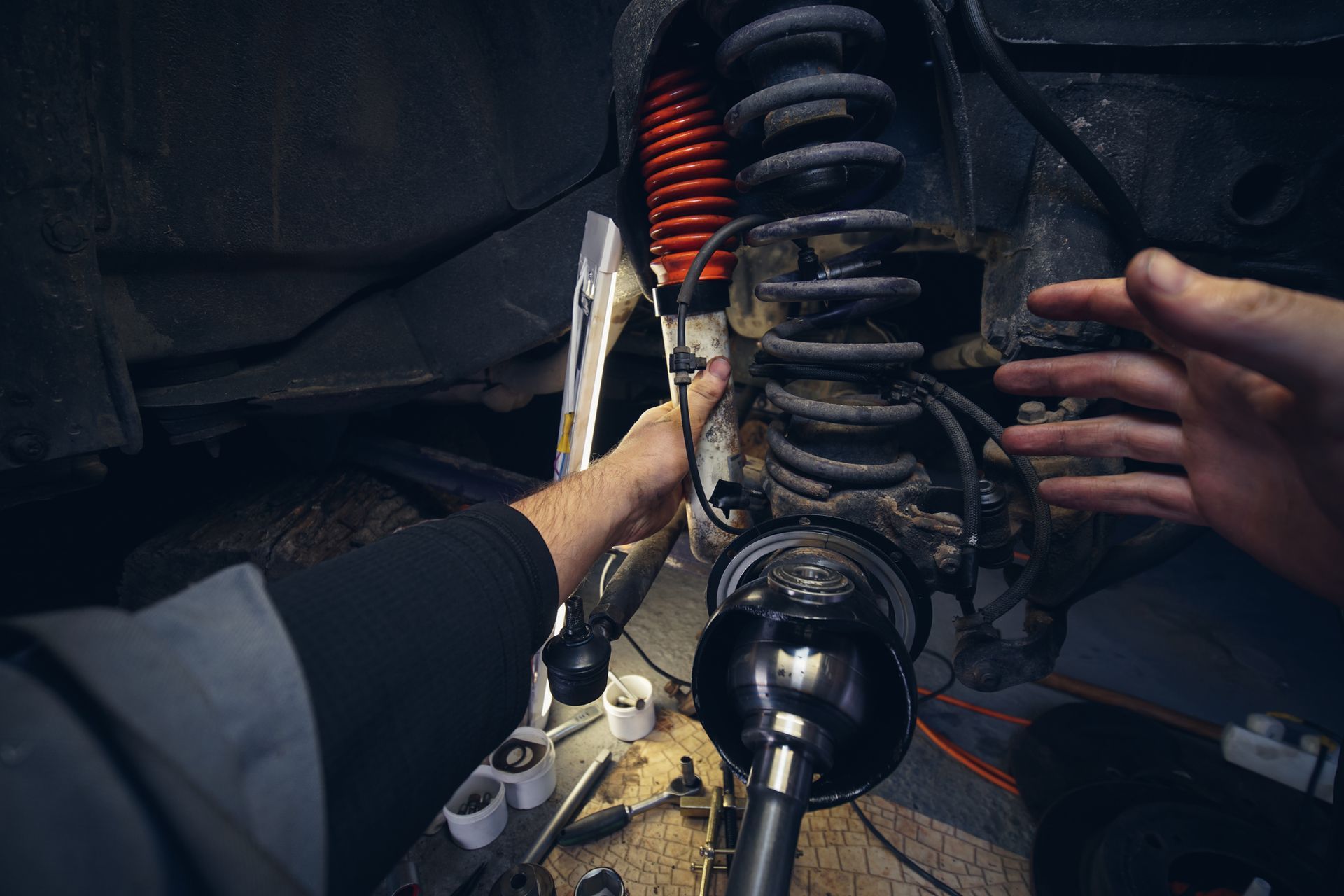 A man is working on a car suspension in a garage.