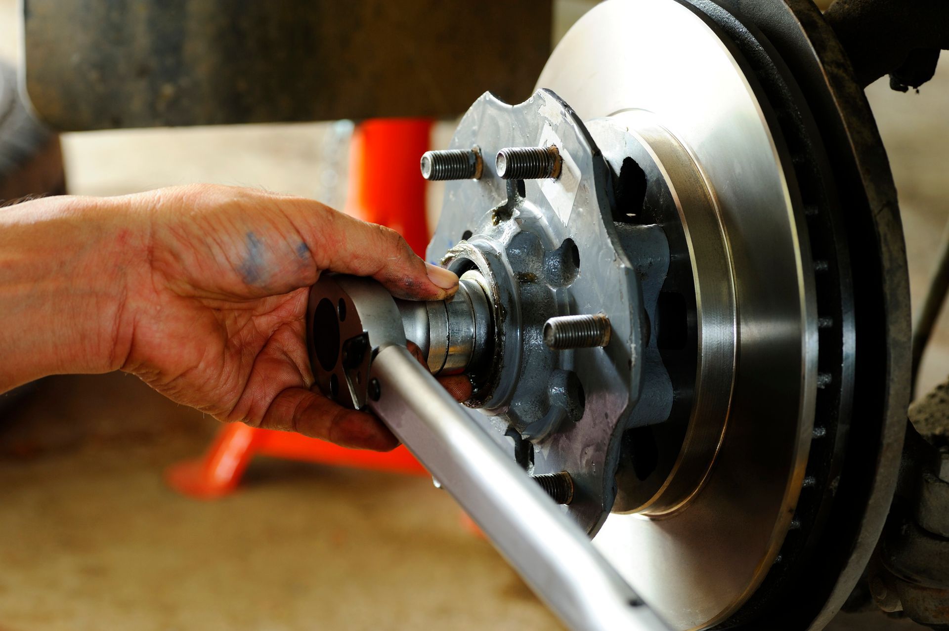 A person is working on a brake disc with a wrench.