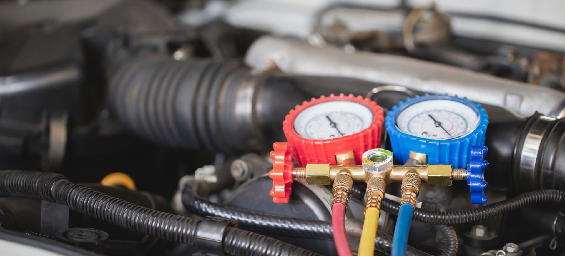 A close up of a car engine with two gauges on it.