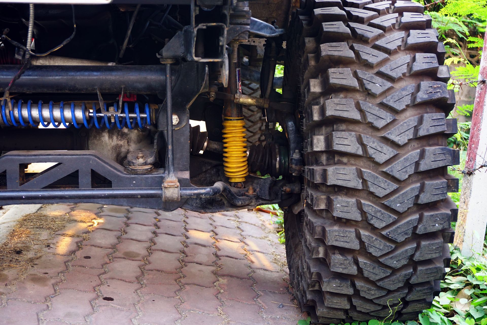 A truck with a large tire is parked on a brick road.