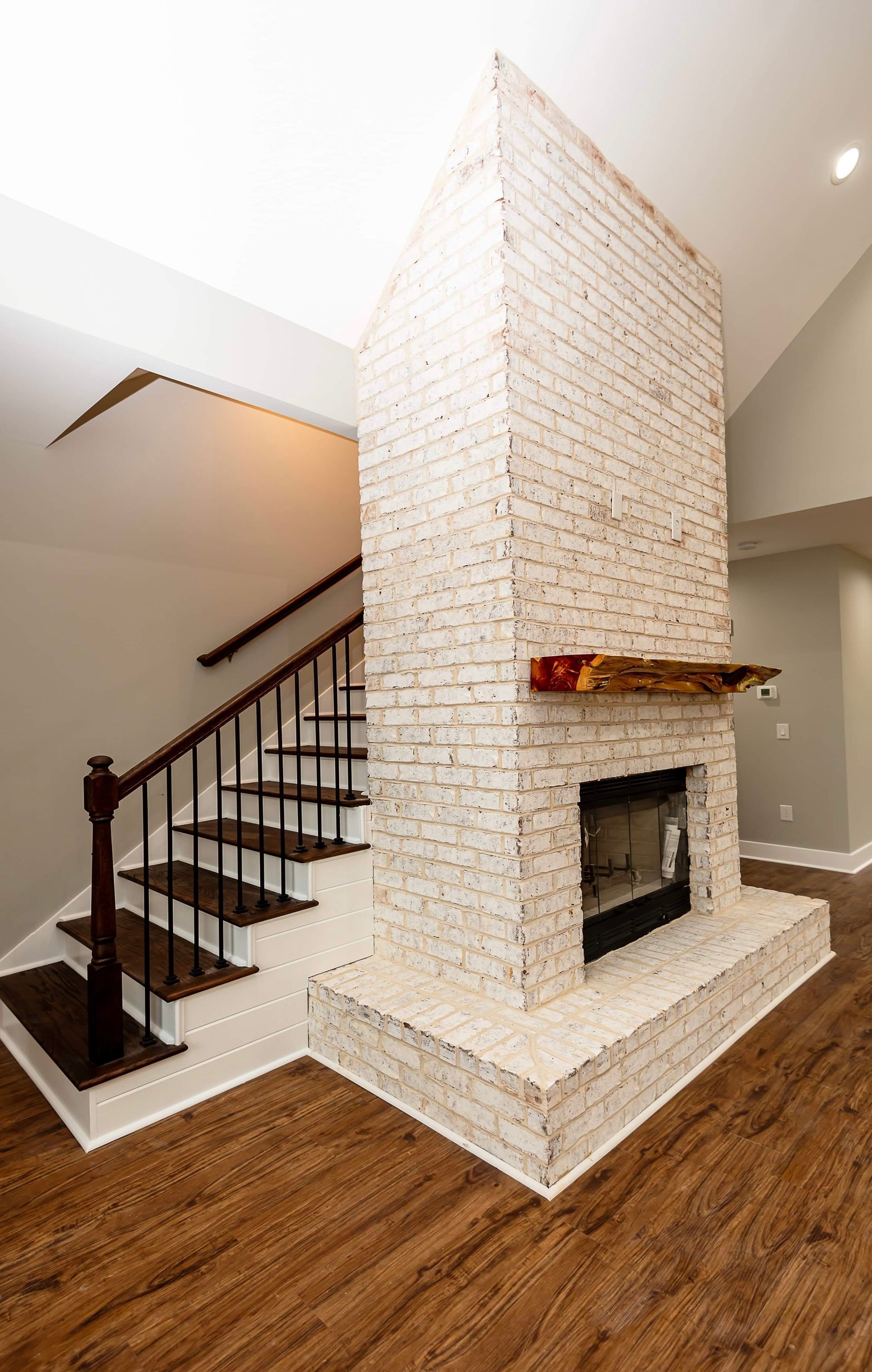 There is a fireplace in the middle of the room next to the stairs.