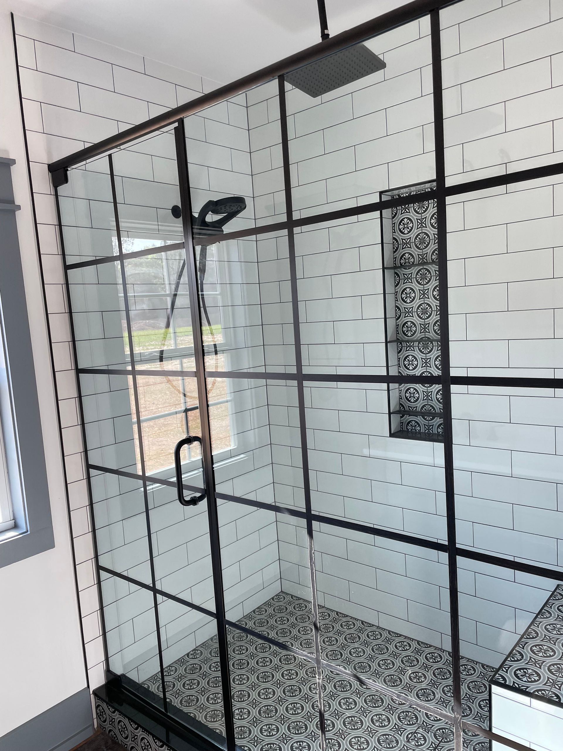 A bathroom with a walk in shower with a black frame