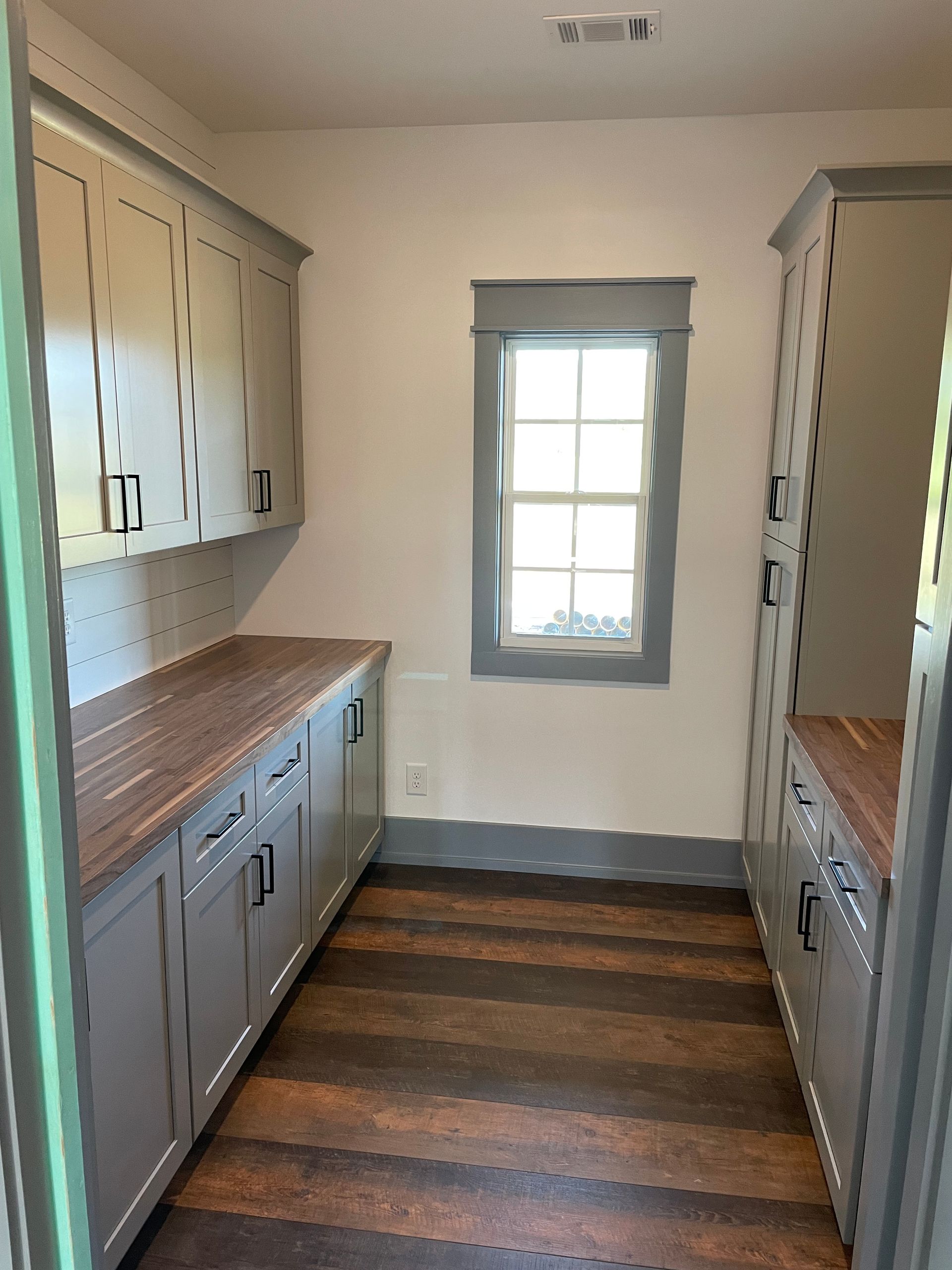 A kitchen with gray cabinets and a window
