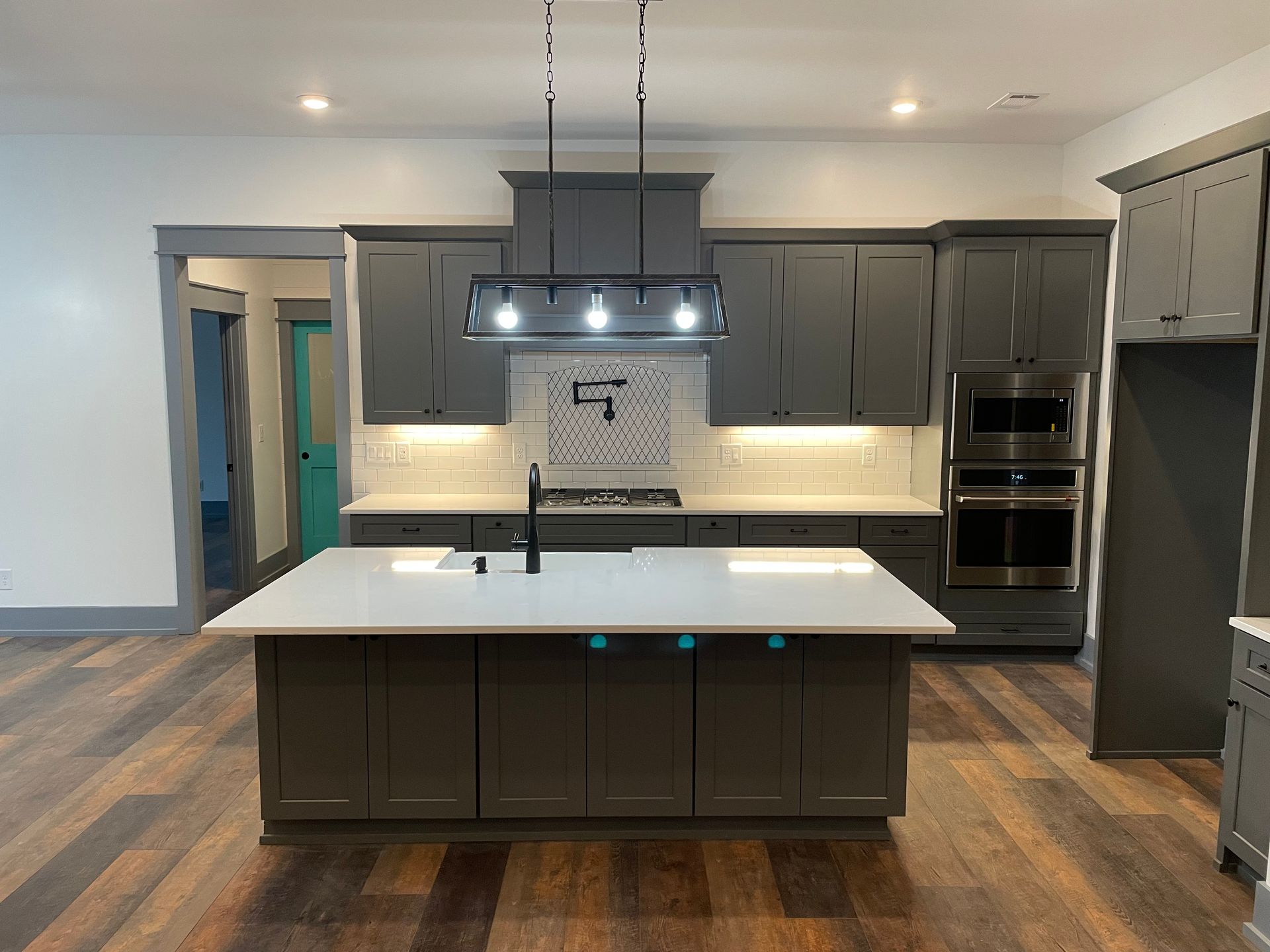 A kitchen with gray cabinets and a large island in the middle.