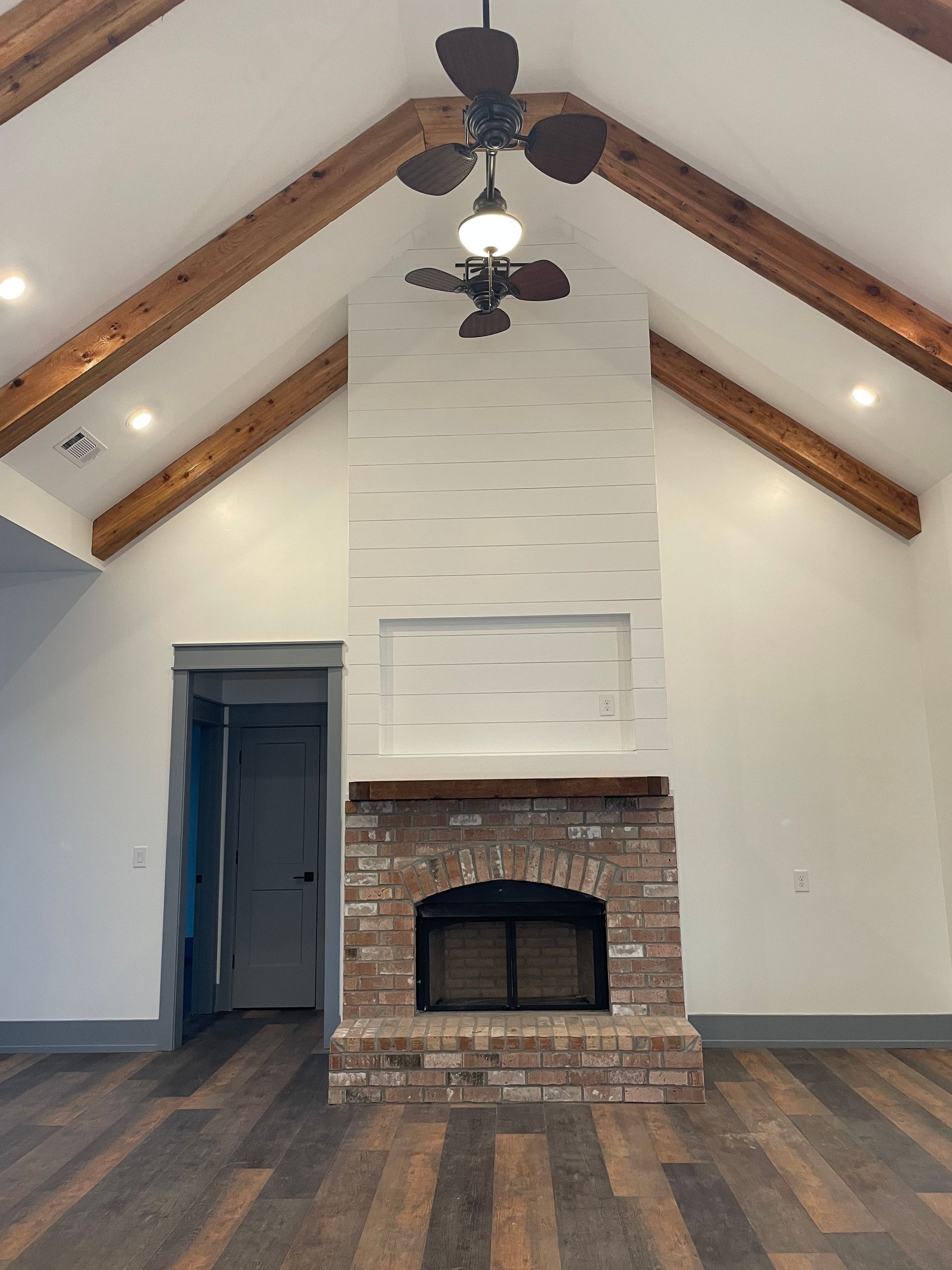 A living room with a fireplace and a ceiling fan.