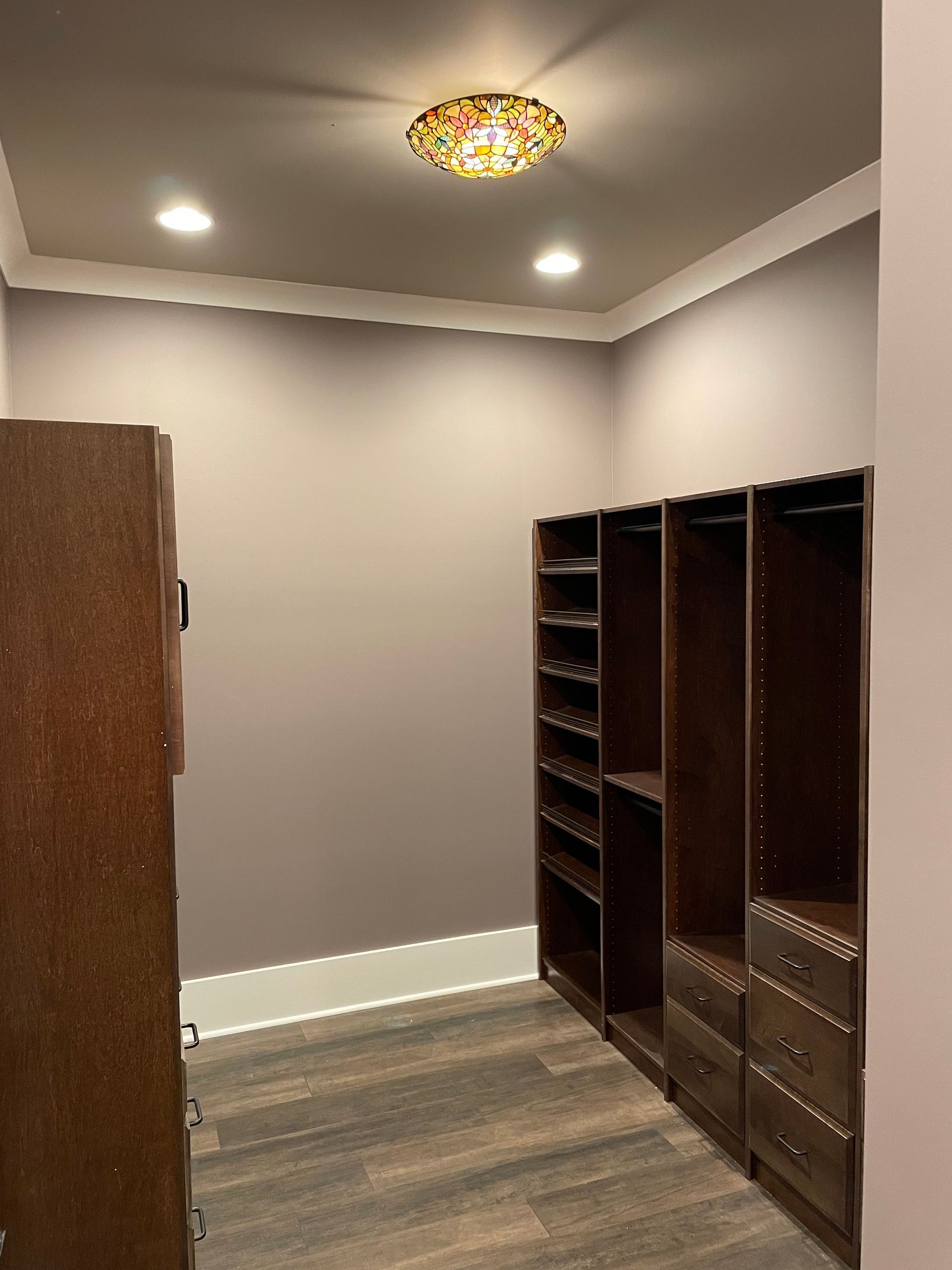 A walk in closet with a stained glass light fixture on the ceiling.