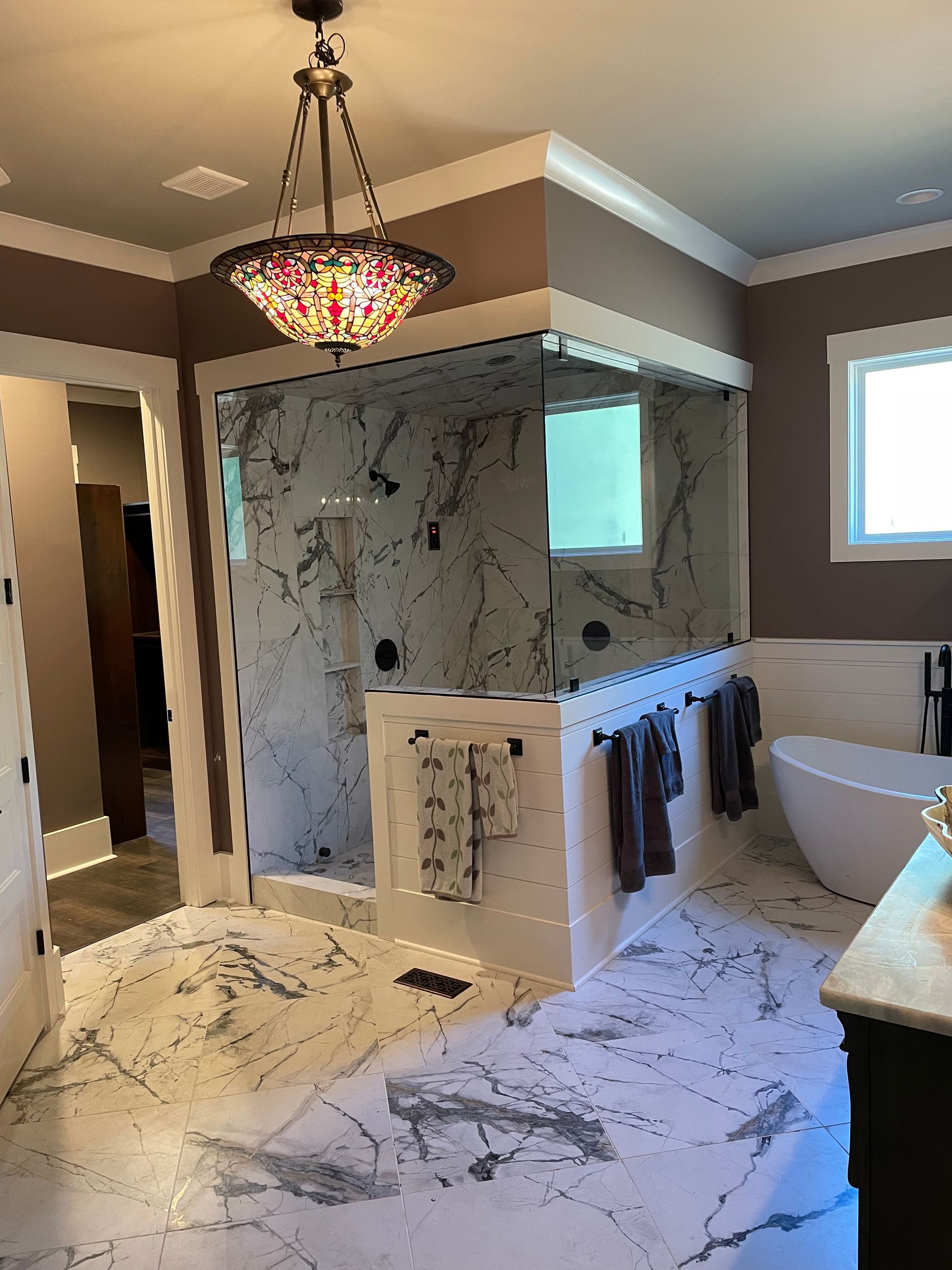 A bathroom with a tub , shower , and chandelier.