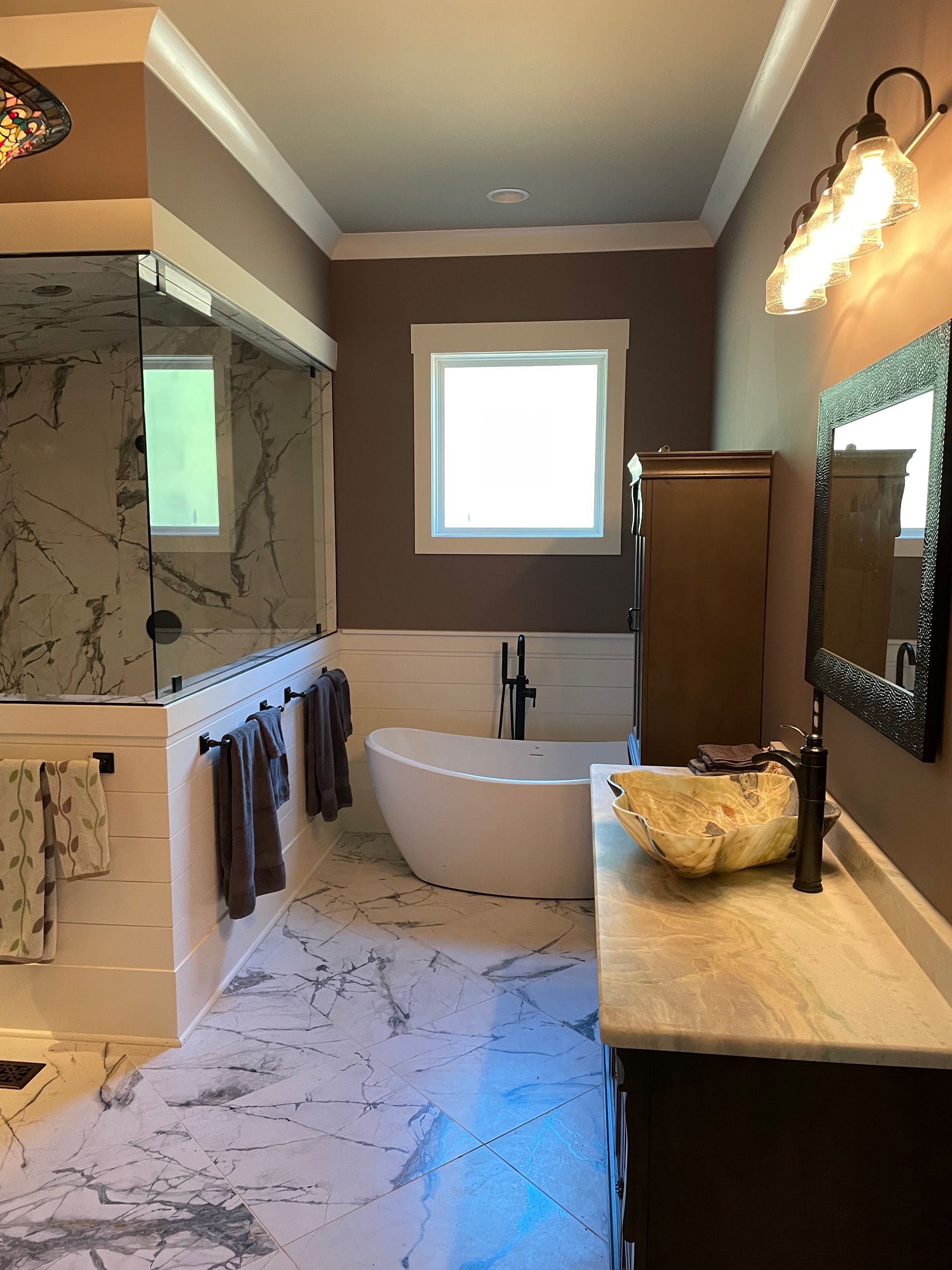 A bathroom with a tub , sink , mirror and window