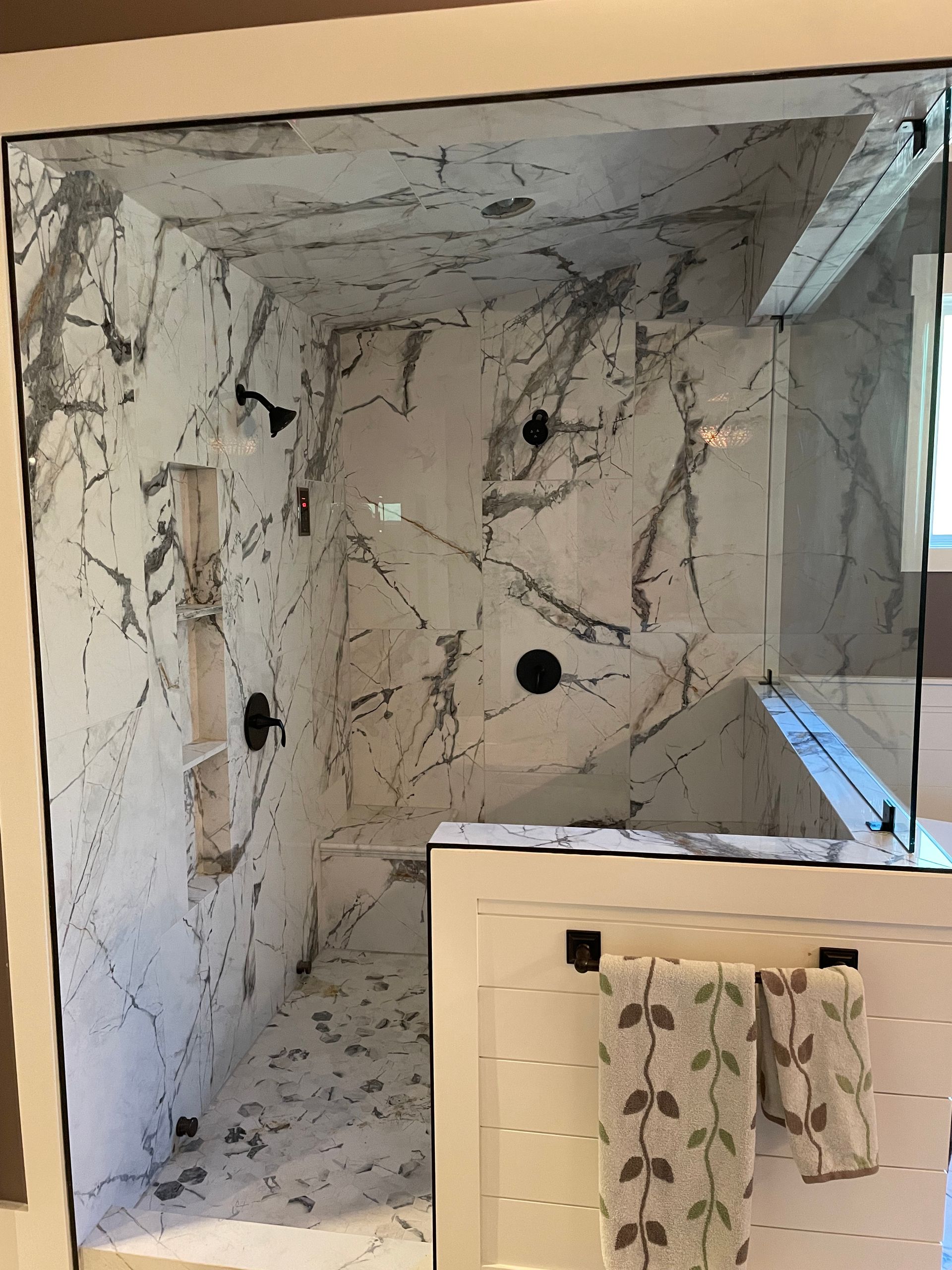 A bathroom with marble walls and a walk in shower