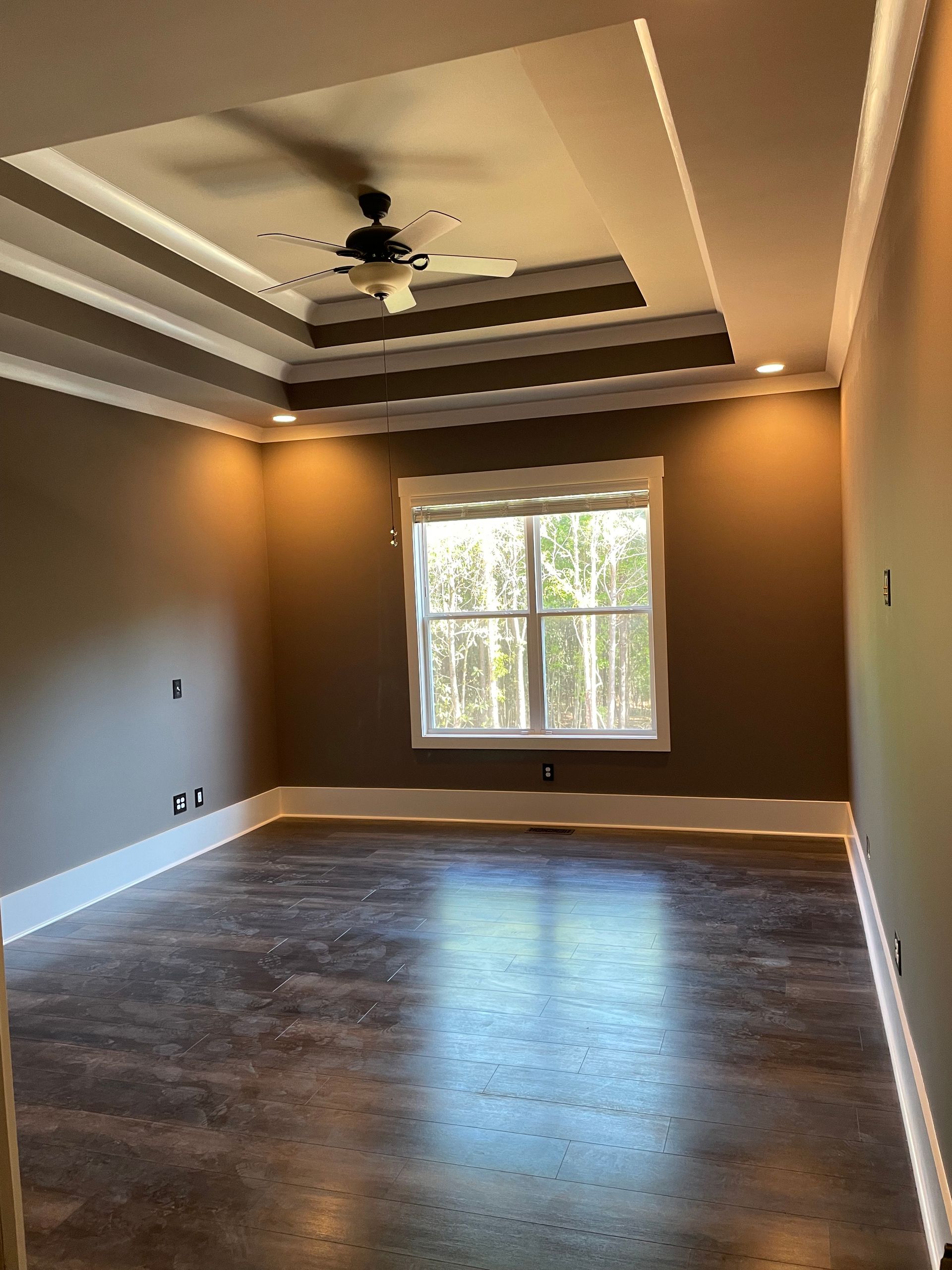 An empty room with a ceiling fan and a window.