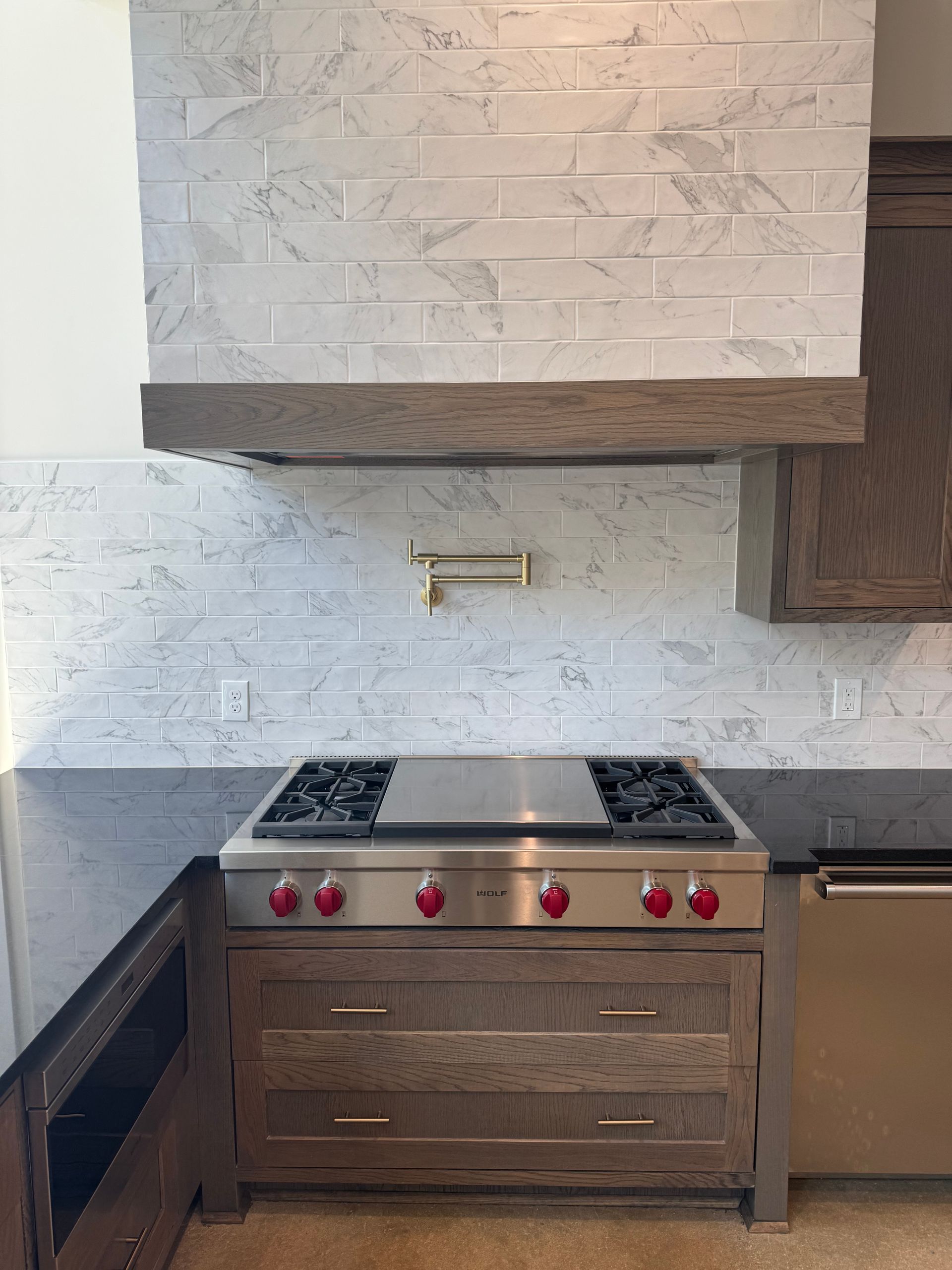 A kitchen with a stove top oven and a hood above it.